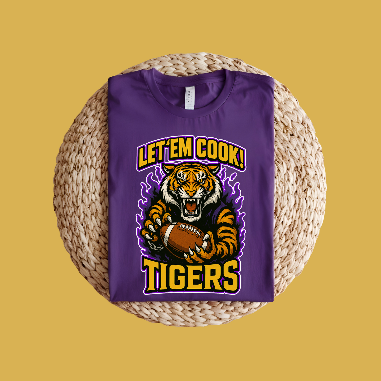 Purple t-shirt with tiger graphic and 'Let 'Em Cook! Tigers' text on a woven surface. Let'em Cook Tigers Bold Graphic T-Shirt - Let'Em Cook Tigers Football Tee