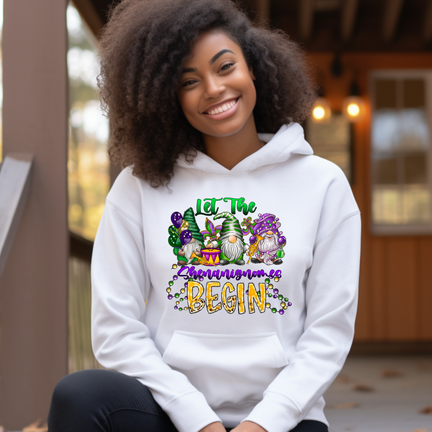Person wearing a white hoodie with a colorful design and text, sitting outdoors.