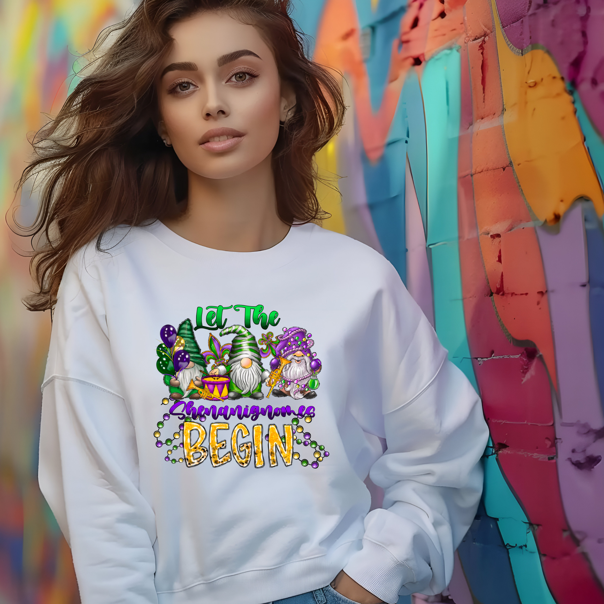Woman wearing a white sweatshirt with a colorful graphic and text, standing in front of a multicolored wall.