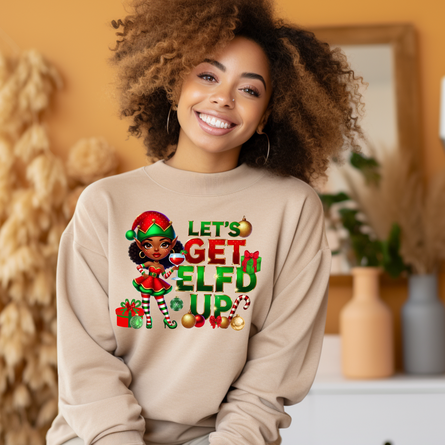 Woman wearing a beige sweatshirt with a Christmas-themed design and text.