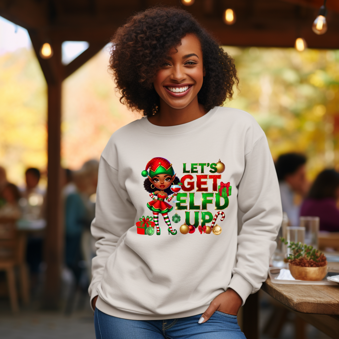 Woman wearing a sweatshirt with an elf graphic and text in an outdoor setting