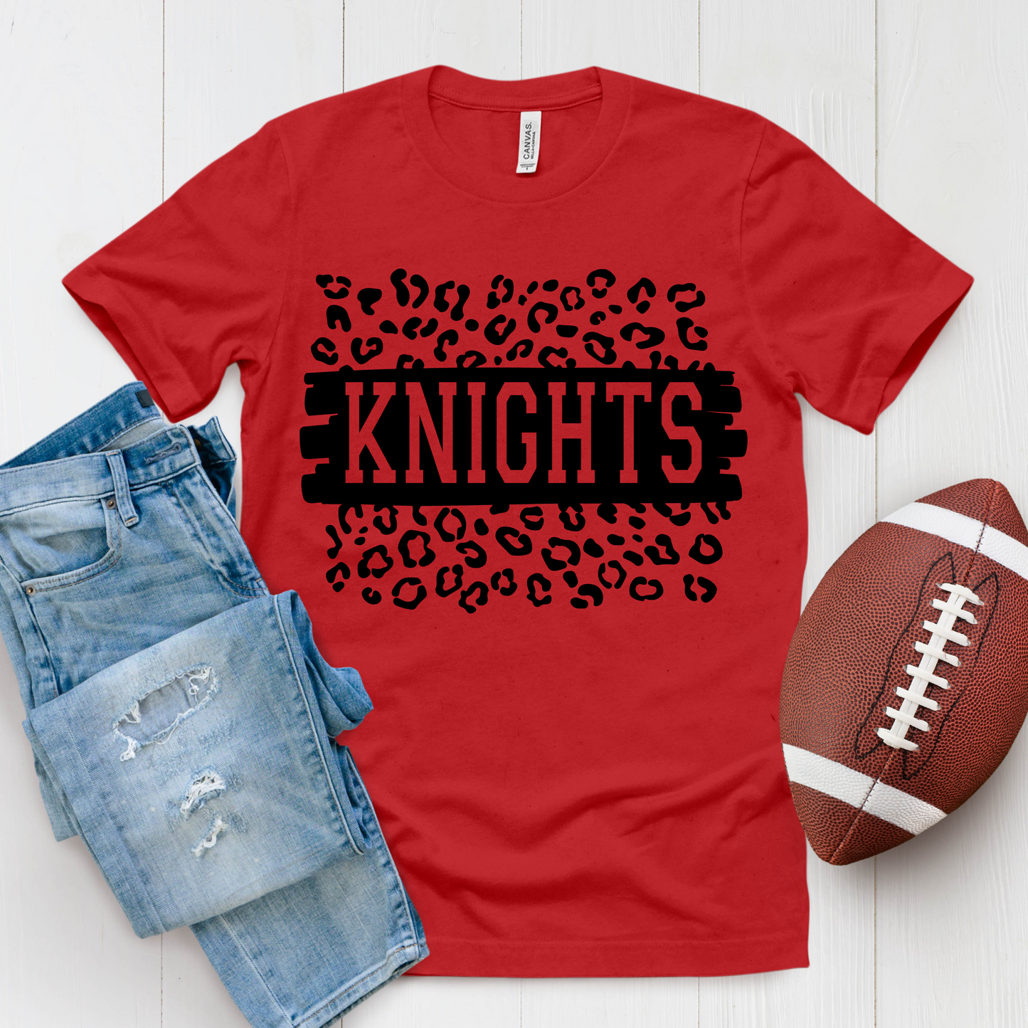 Red t-shirt with 'KNIGHTS' design, blue jeans, and football on a white background Knights School Spirit Shirt - Knights Leopard - School Pride Graphic T-Shirt