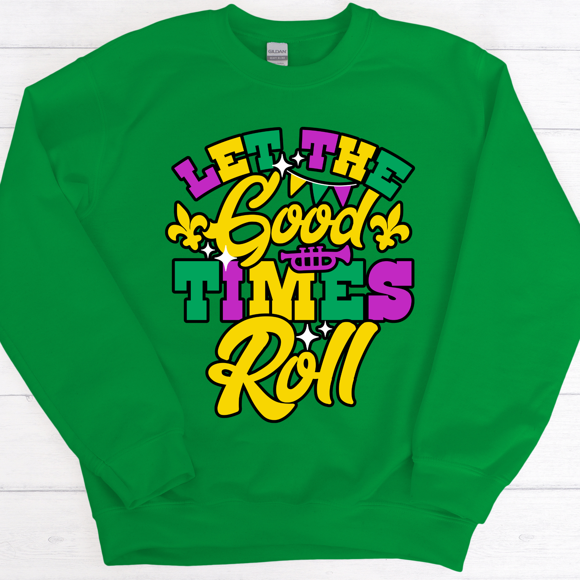 Green sweatshirt with colorful text 'Let the Good Times Roll' on a white wooden background