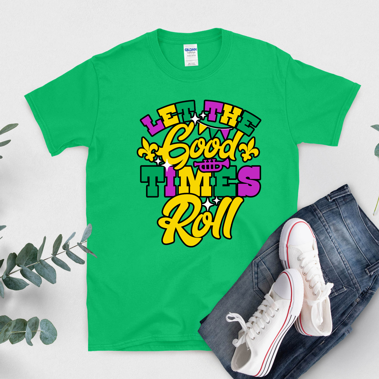 Green t-shirt with colorful text 'Let the Good Times Roll' on a white background with jeans and sneakers.