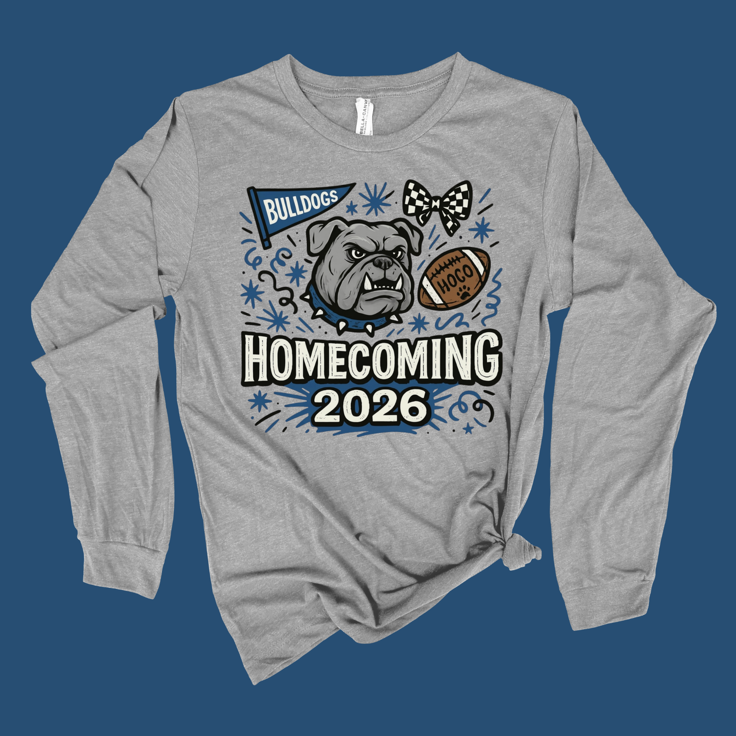 A heather gray long-sleeve t-shirt with a 'Homecoming 2026' bulldog graphic, displayed flat against a solid dark blue background.