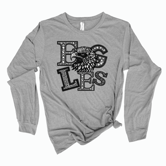 A heather gray long-sleeve t-shirt with a distressed black graphic on the front that reads 'EGGS' with an eagle head illustration, styled with a knot at the bottom hem, on a white background.