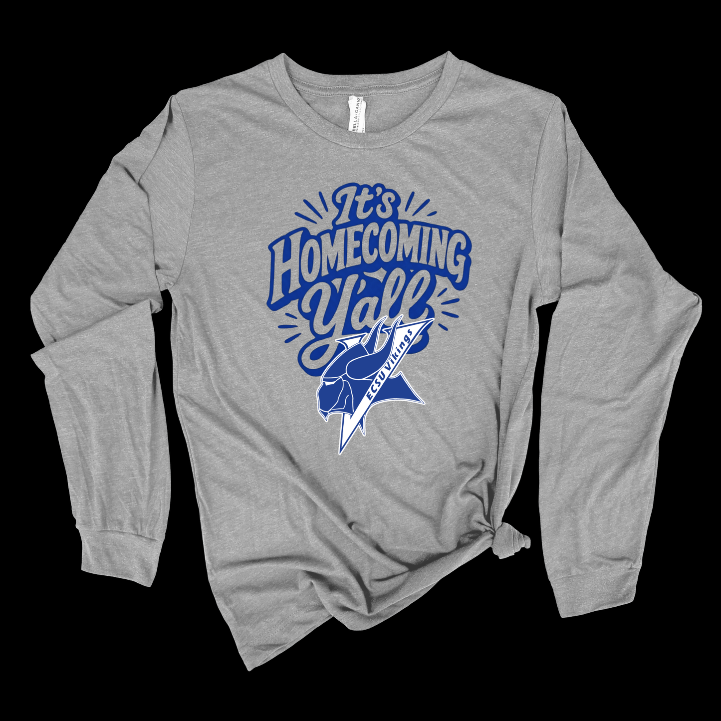 A heather gray long-sleeve t-shirt with a blue graphic on the front that reads 'It's Homecoming Yell' with a football player silhouette and the text 'BETWEEN FIFTHS', displayed on a solid black background.