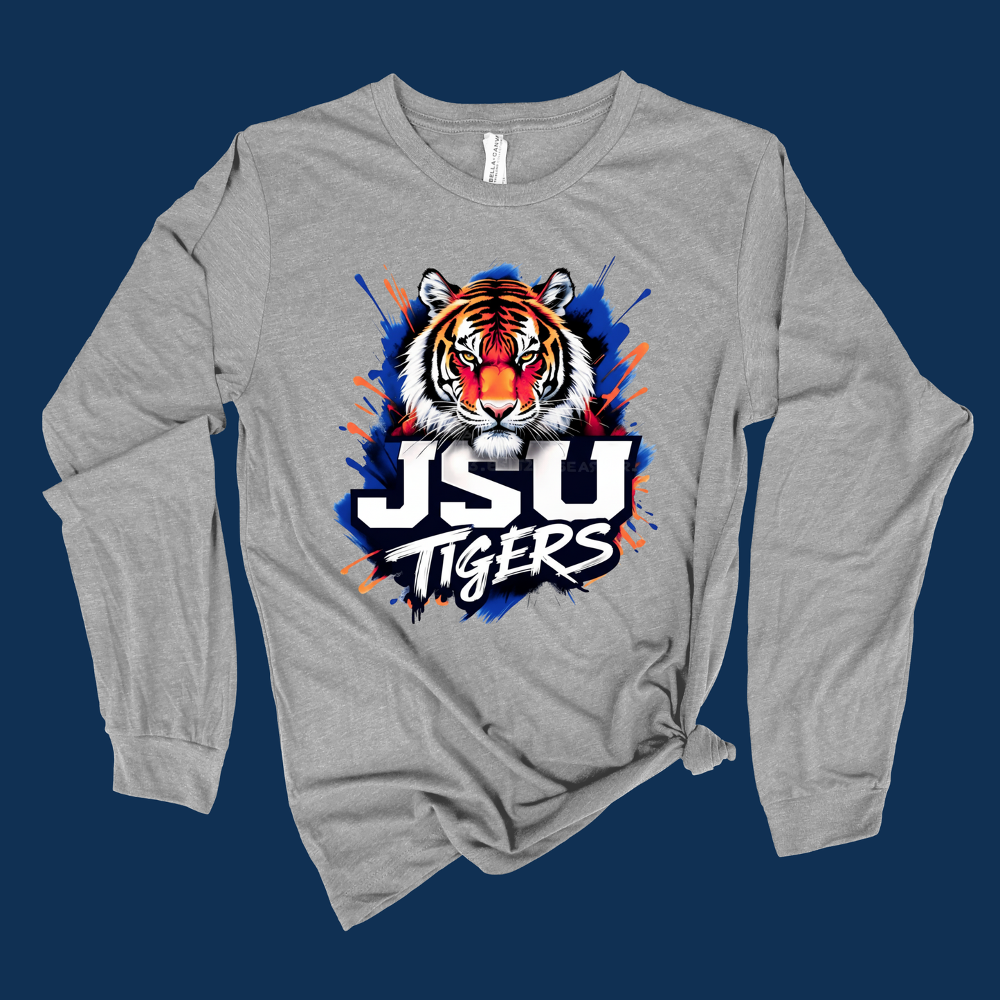 A heather gray long-sleeve t-shirt with a front graphic of a tiger head and the text 'JSU TIGERS' in white, blue, and orange, displayed on a dark navy blue background.