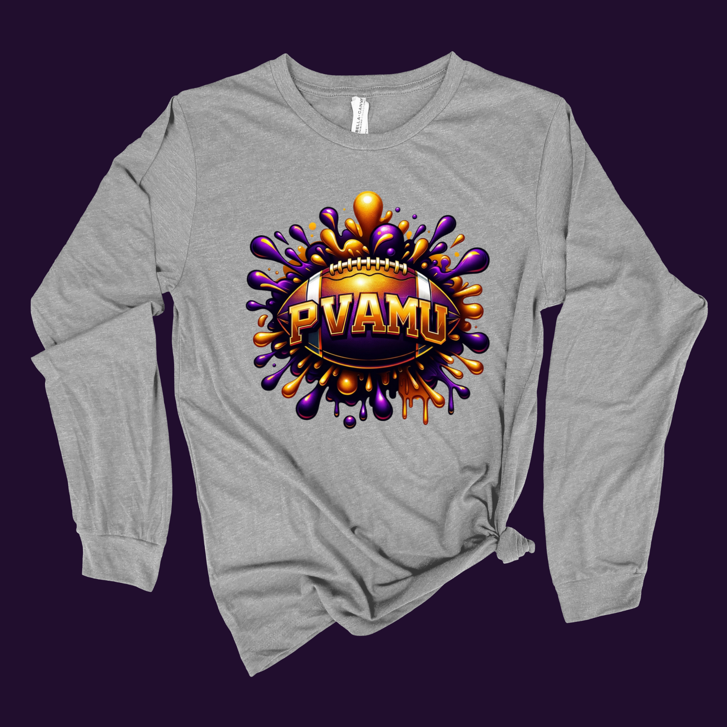 A heather gray long-sleeve t-shirt with a knotted hem, featuring a large graphic print of a football surrounded by purple and orange paint splatters with the text 'PVAMU' in gold.