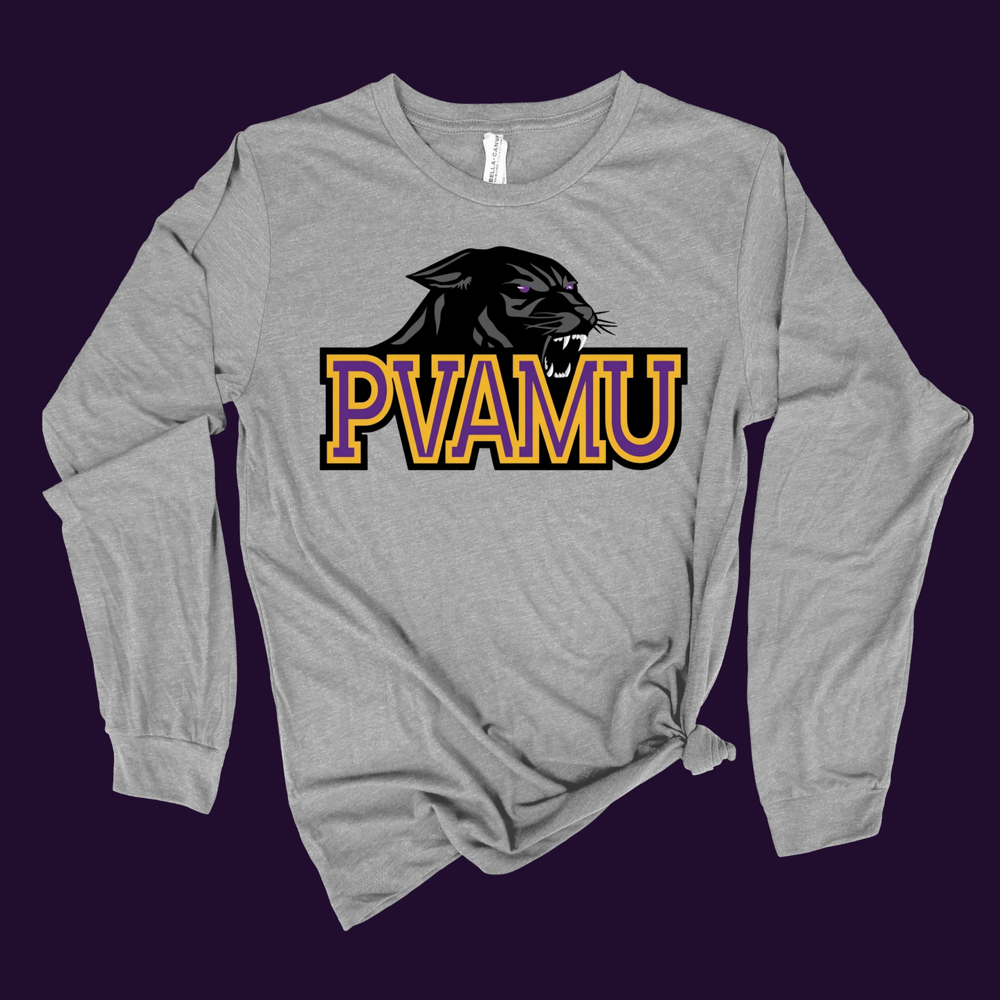 A heather gray long-sleeve t-shirt with a knotted hem, featuring a graphic of a black panther head above the text 'PVAMU' in yellow and purple outlined block letters. The shirt is displayed flat against a solid dark purple background.