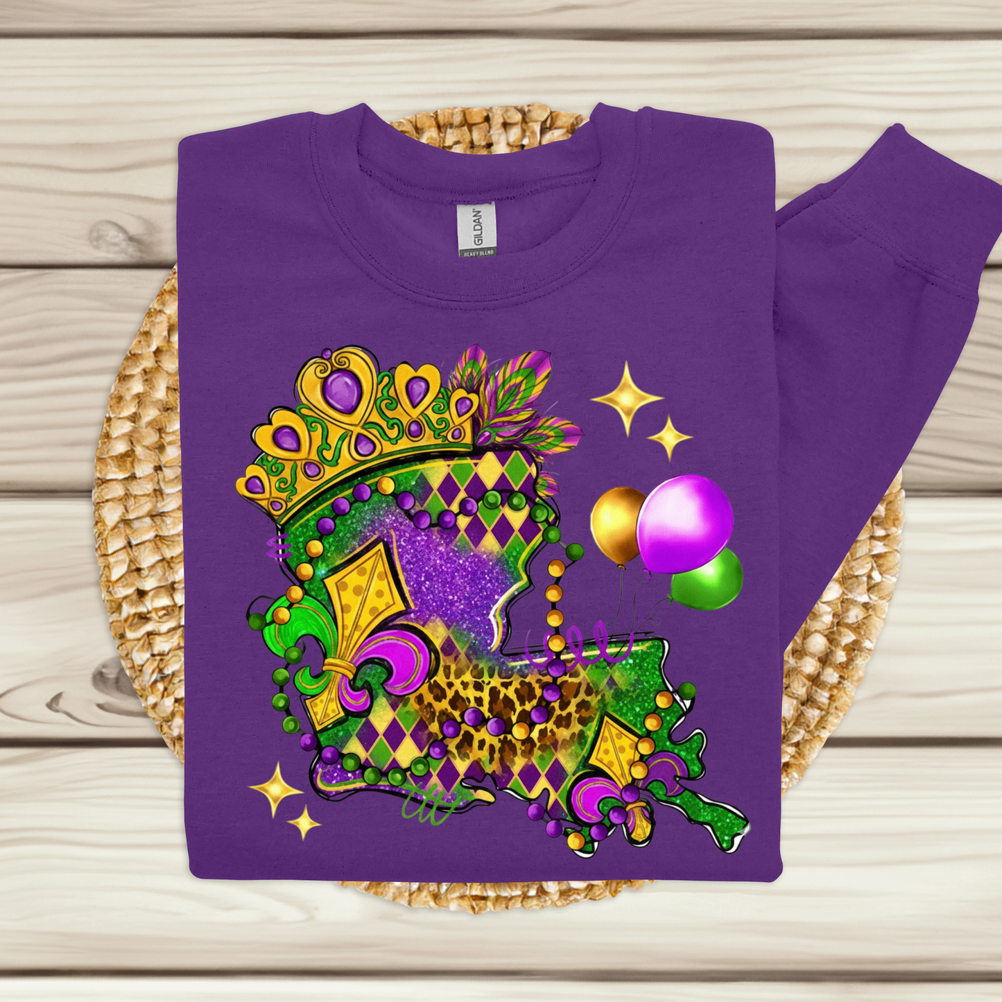 Purple sweatshirt with Mardi Gras-themed design on a woven mat