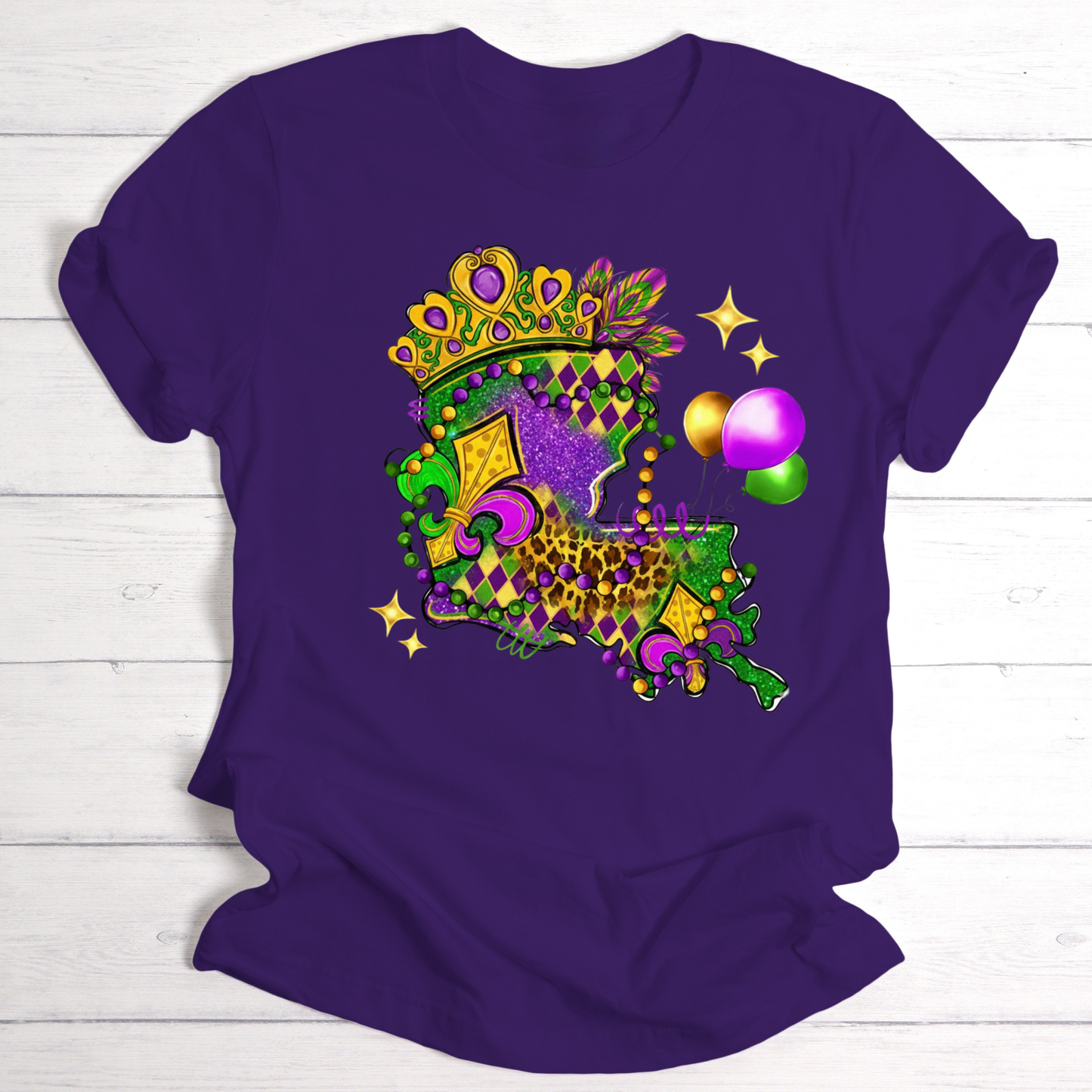 Purple t-shirt with a colorful Mardi Gras design on a white wooden background
