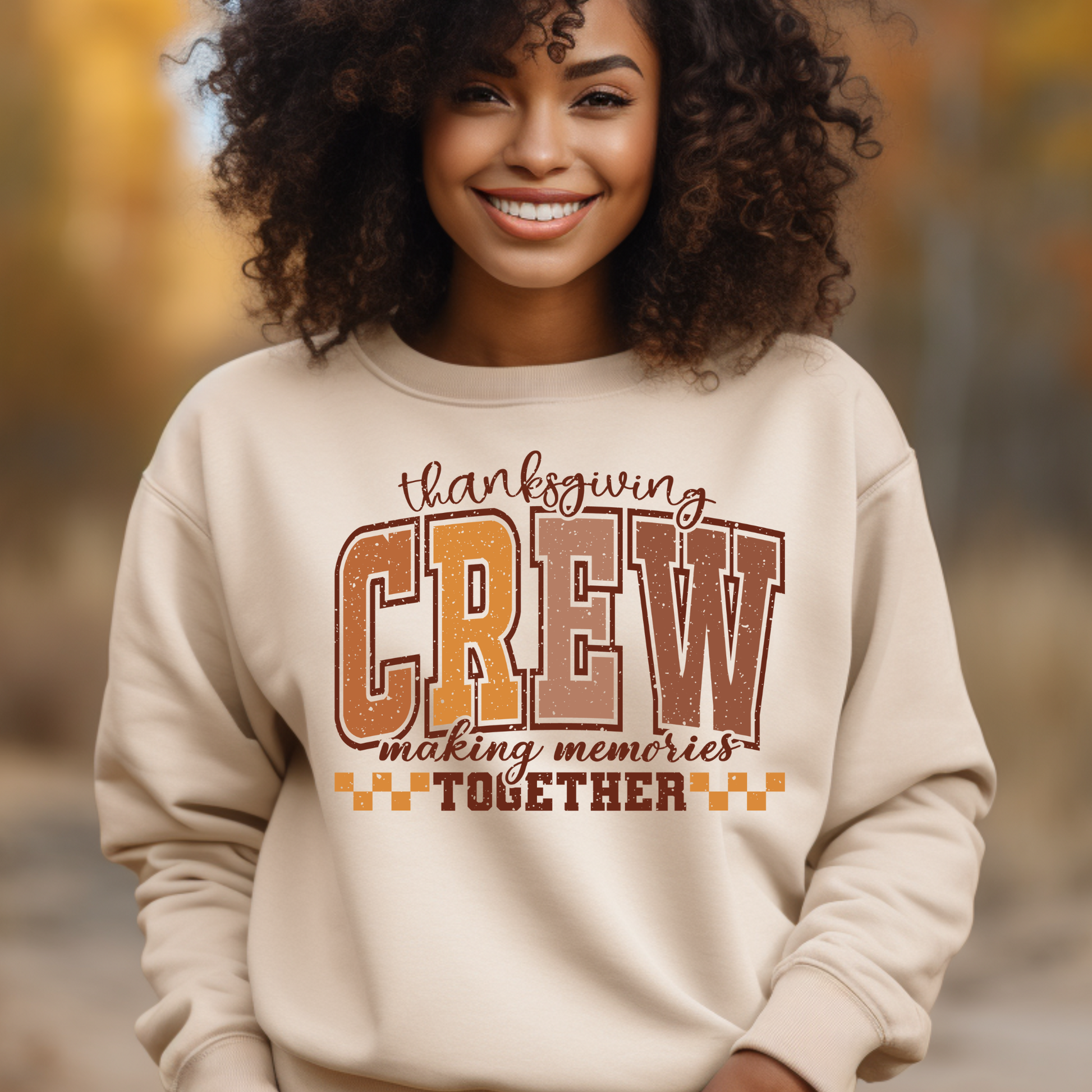 Woman wearing a beige sweatshirt with 'Thanksgiving Crew making memories together' text in an outdoor setting.