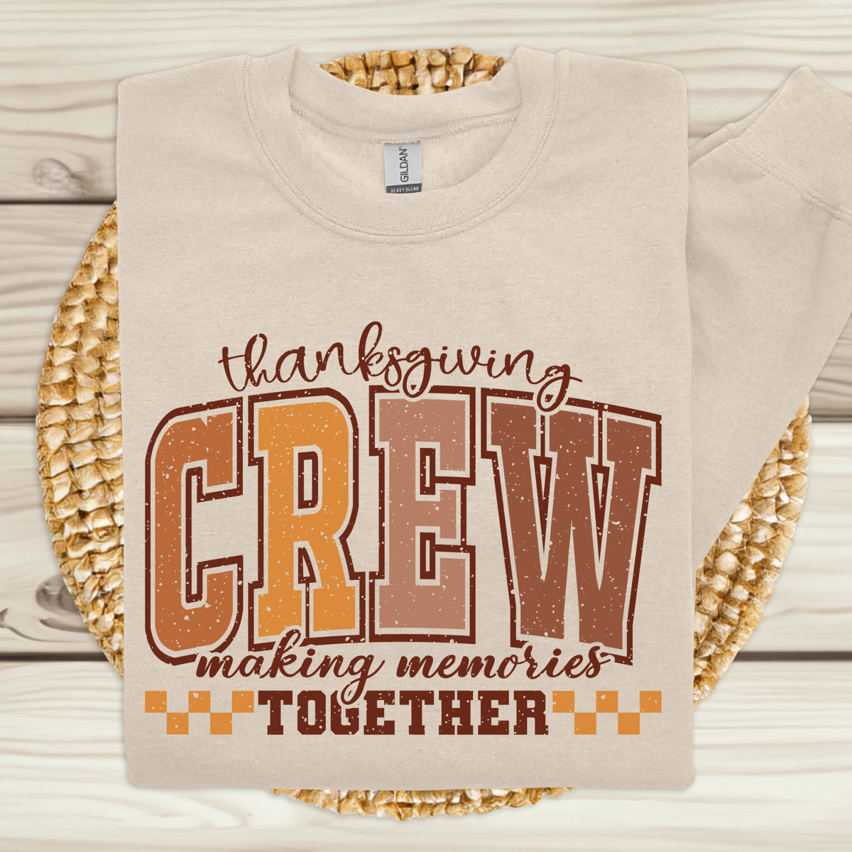 Beige sweatshirt with 'Thanksgiving Crew making memories together' text on a woven mat background