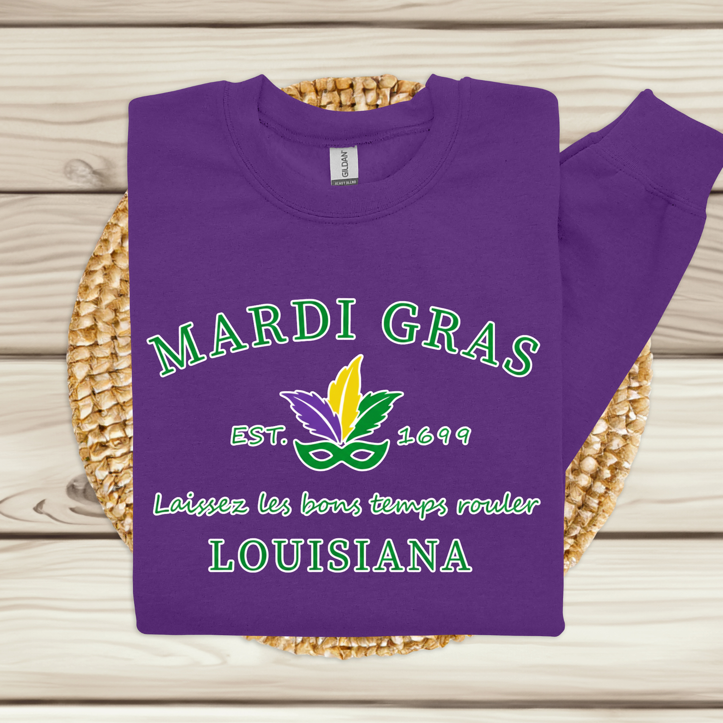 Purple sweatshirt with Mardi Gras-themed design on a woven mat