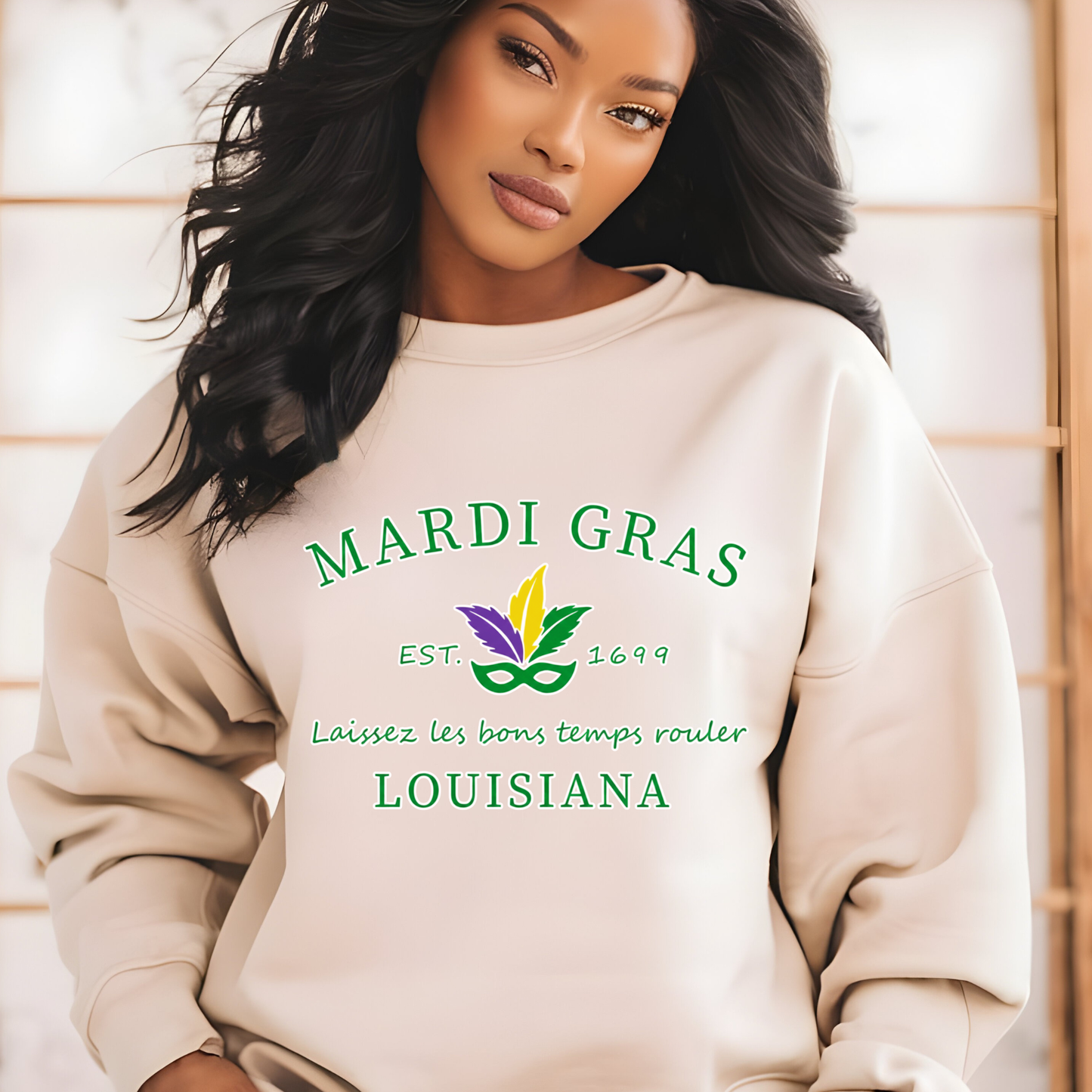 Woman wearing a beige sweatshirt with Mardi Gras-themed text and graphics.