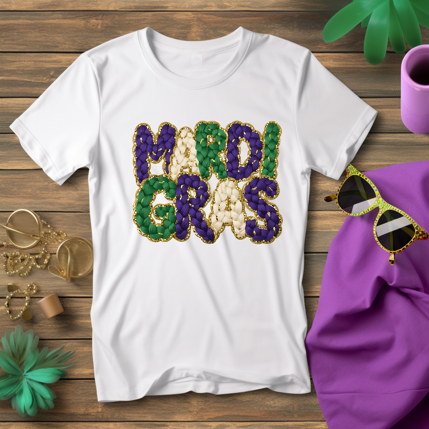 White t-shirt with 'Mardi Gras' text in colorful sequins on a wooden surface with Mardi Gras-themed accessories.