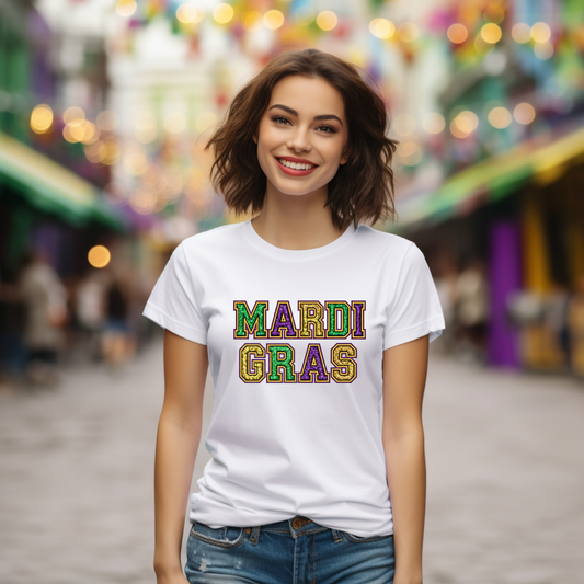 Woman wearing a 'Mardi Gras' t-shirt in a festive setting with blurred lights and decorations.