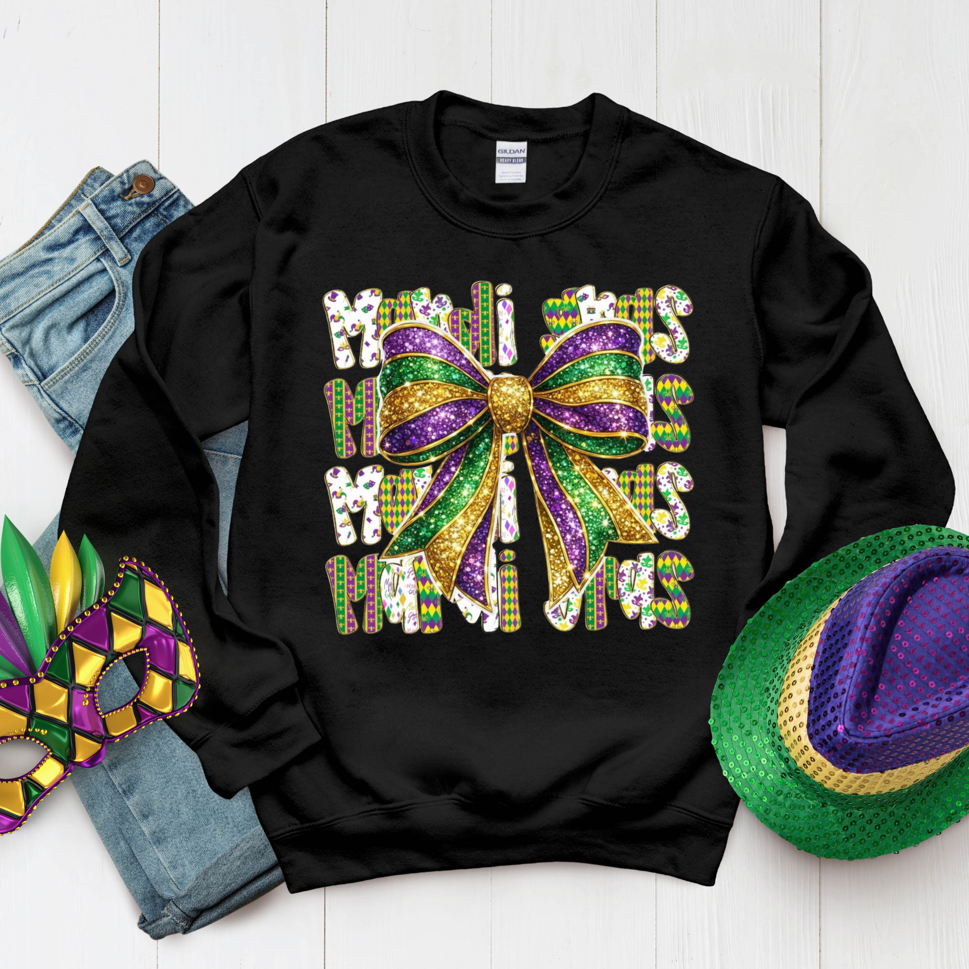 Black sweatshirt with Mardi Gras-themed design on a white surface with Mardi Gras accessories.