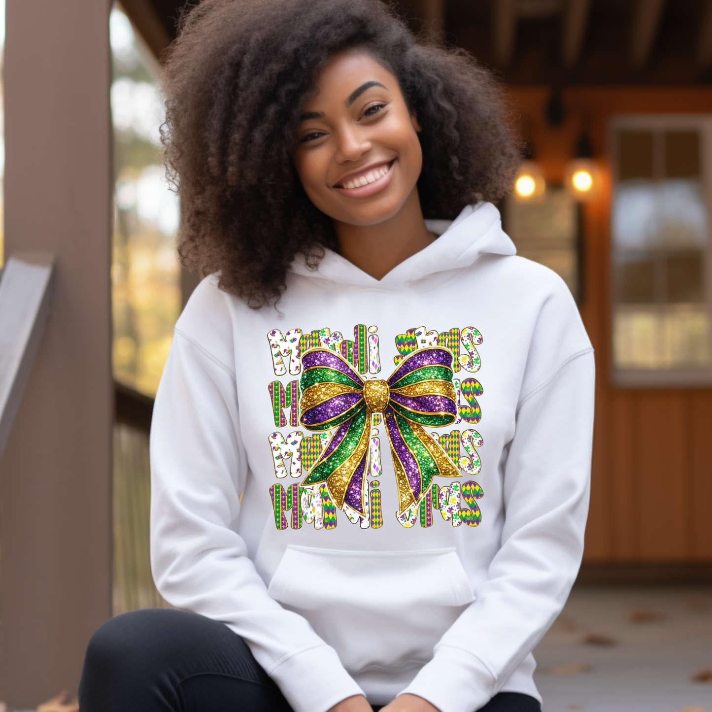Person wearing a white hoodie with a colorful bow design outdoors.