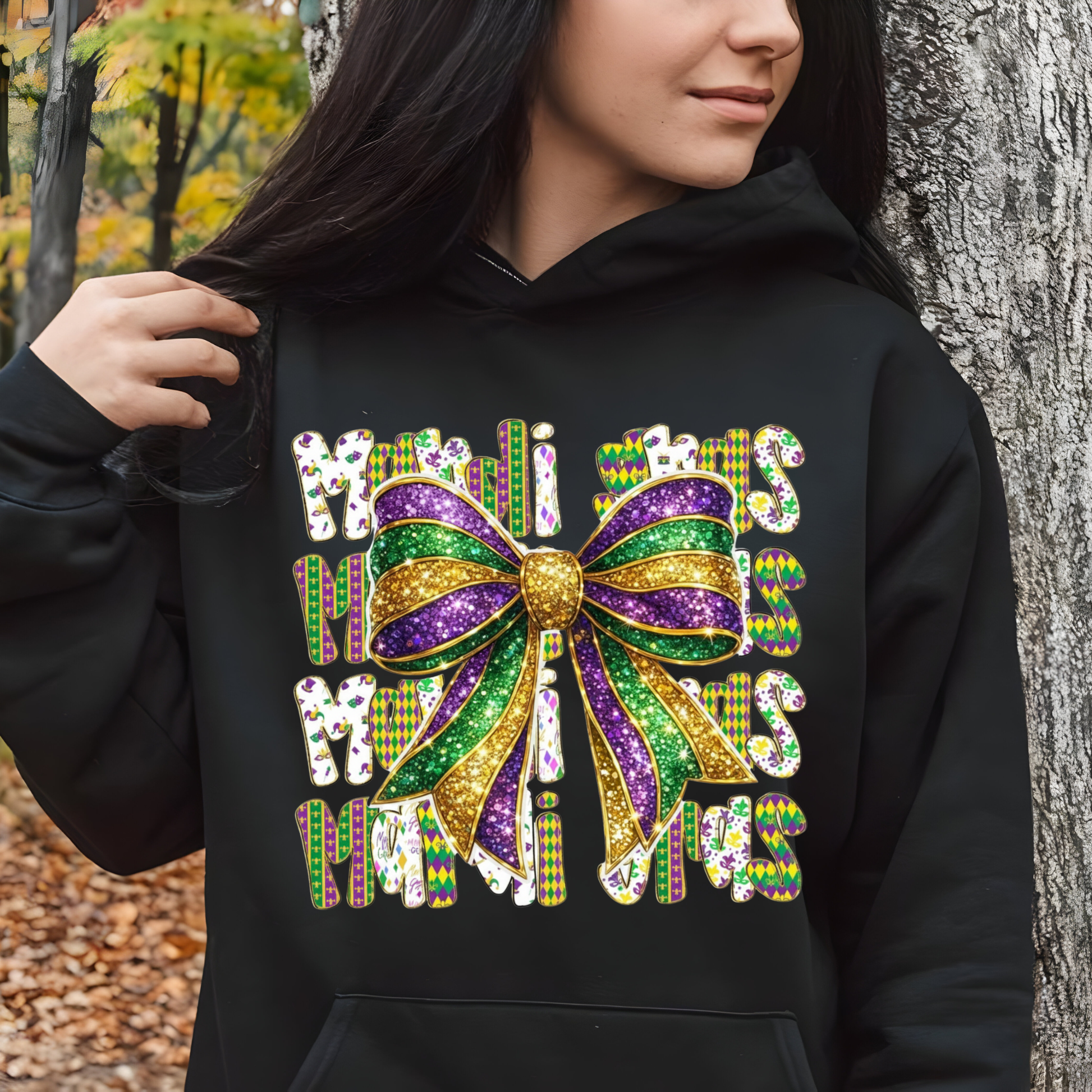 Person wearing a black hoodie with a colorful bow design and text in an outdoor setting.