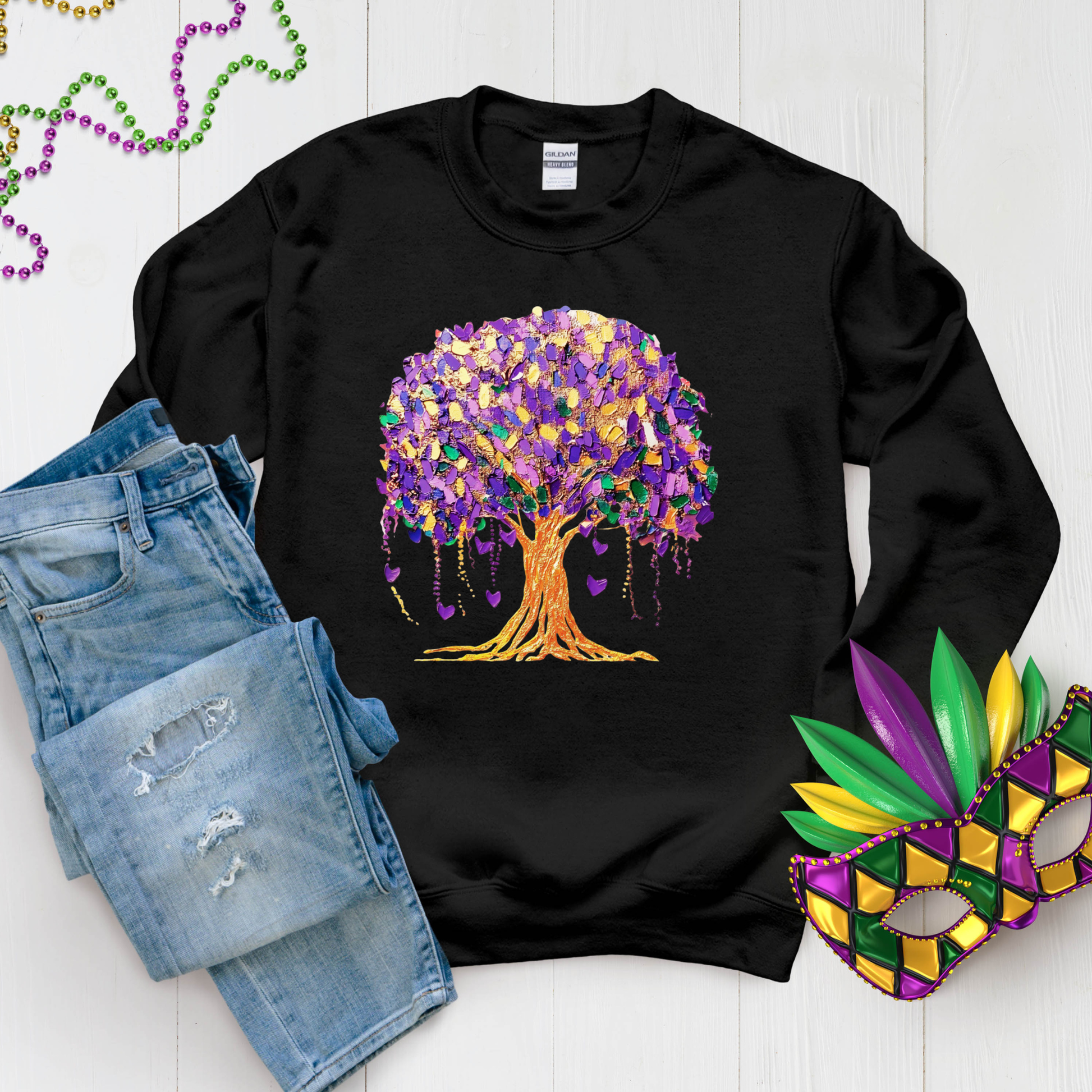 Black sweatshirt with a colorful tree design, paired with denim shorts and Mardi Gras-themed accessories on a light wooden surface.