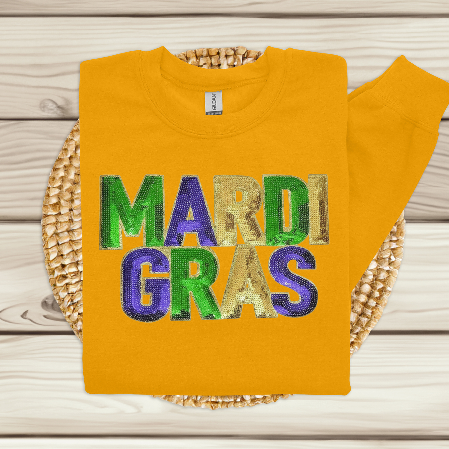 Yellow sweatshirt with 'MARDI GRAS' in colorful letters on a woven basket.