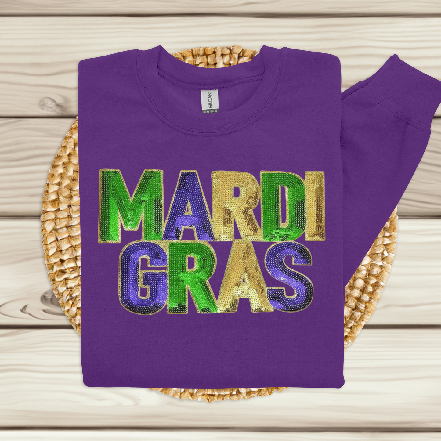 Purple sweatshirt with 'Mardi Gras' text on a woven mat