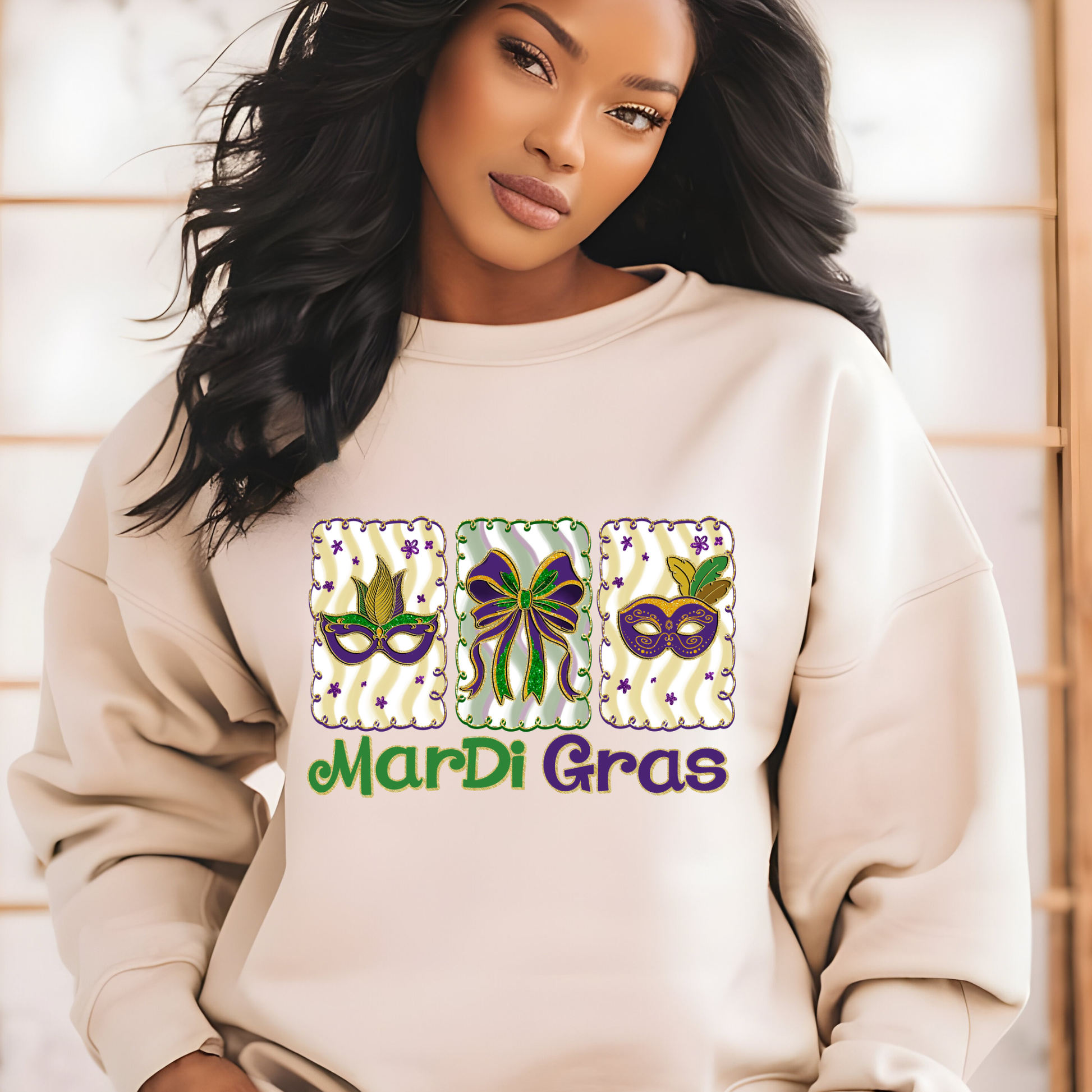 Woman wearing a beige sweatshirt with Mardi Gras-themed designs and text.