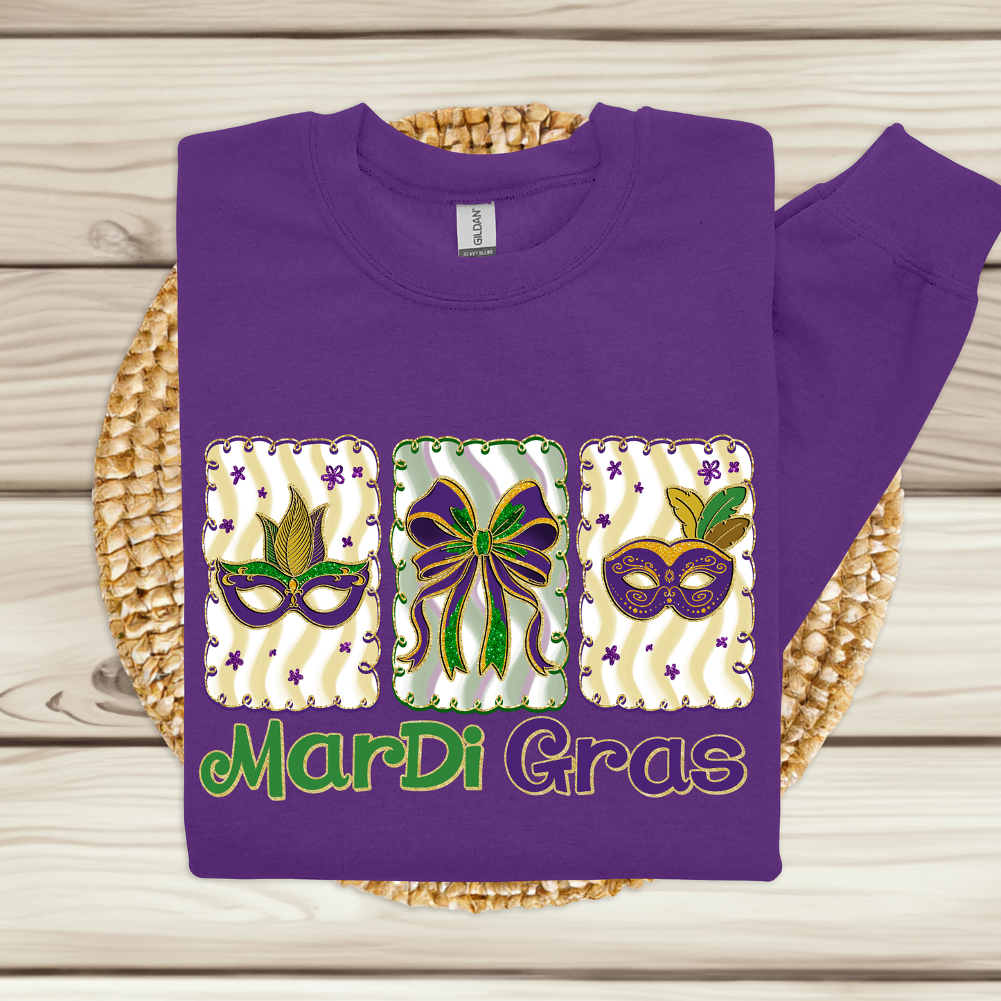Purple sweatshirt with Mardi Gras-themed design on a woven mat