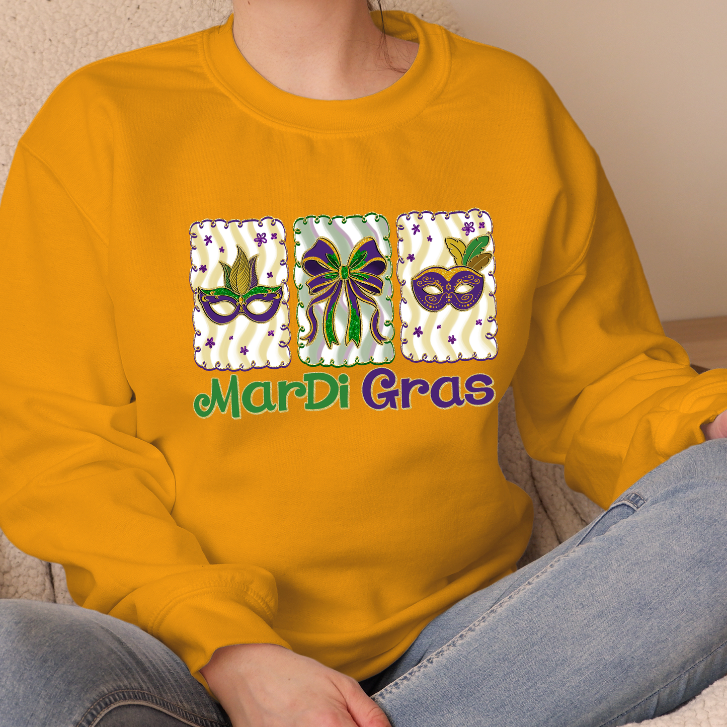 Person wearing a yellow sweatshirt with Mardi Gras-themed designs and text.