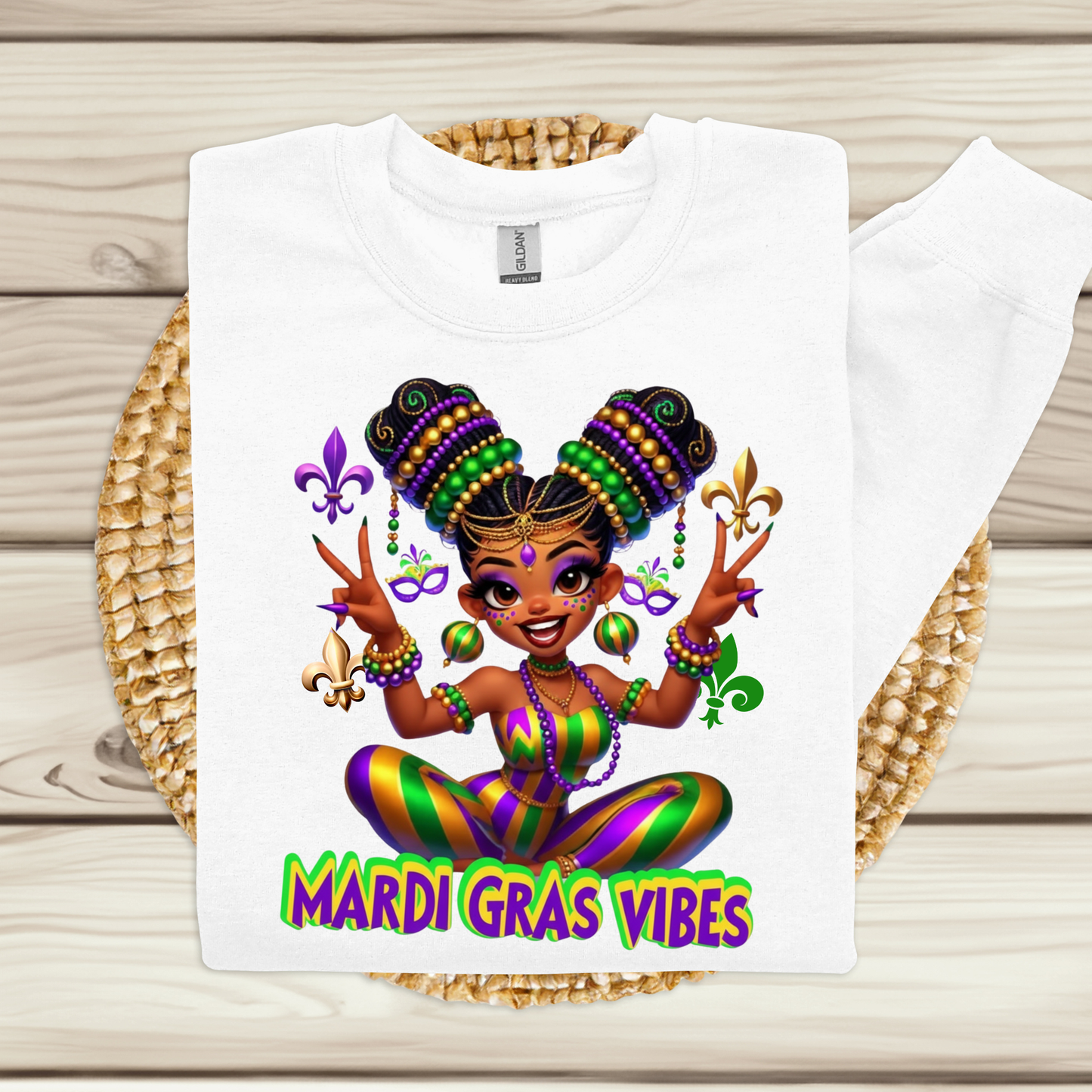 White t-shirt with Mardi Gras-themed design featuring a cartoon character on a woven mat.
