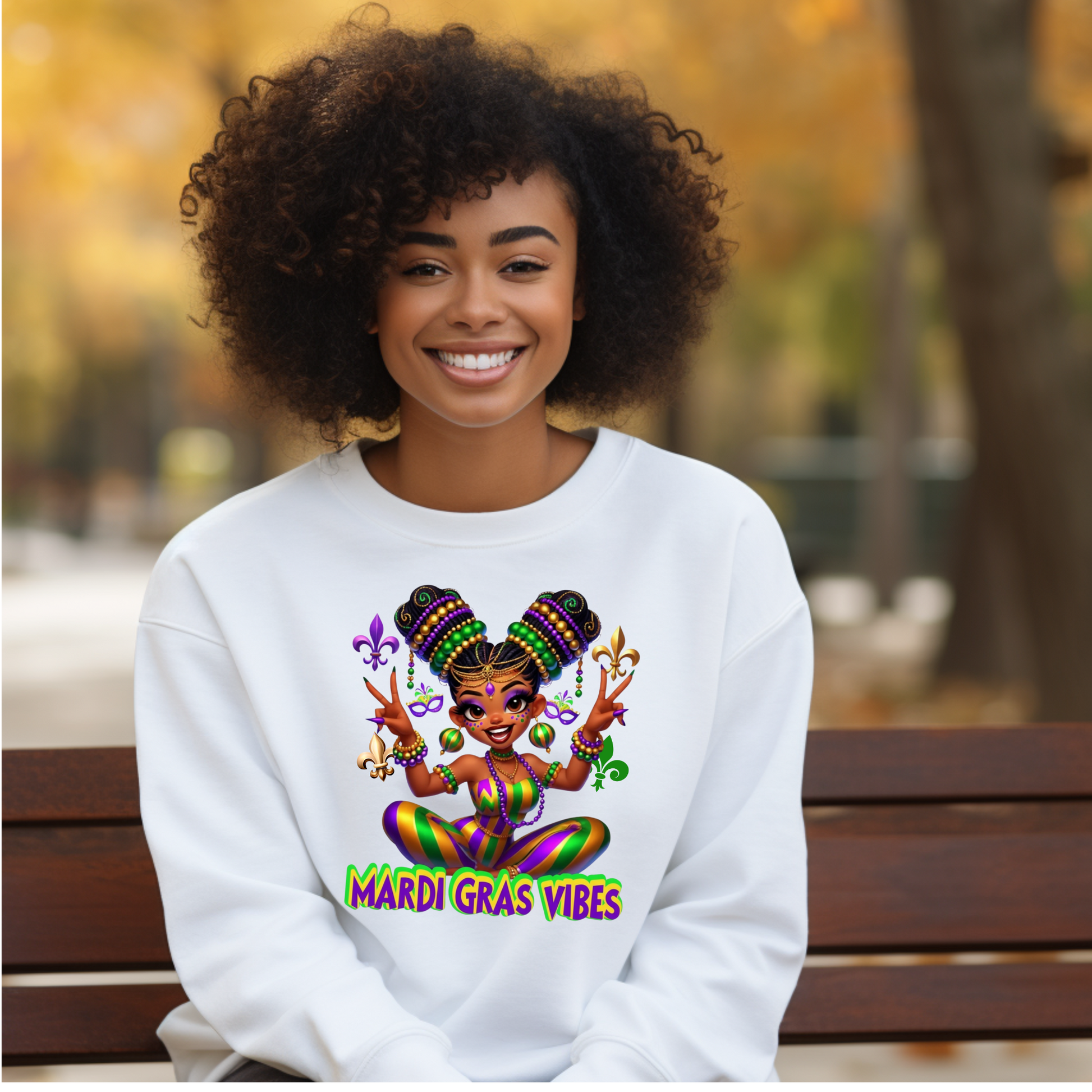 Woman wearing a white sweatshirt with Mardi Gras-themed design sitting on a bench outdoors.