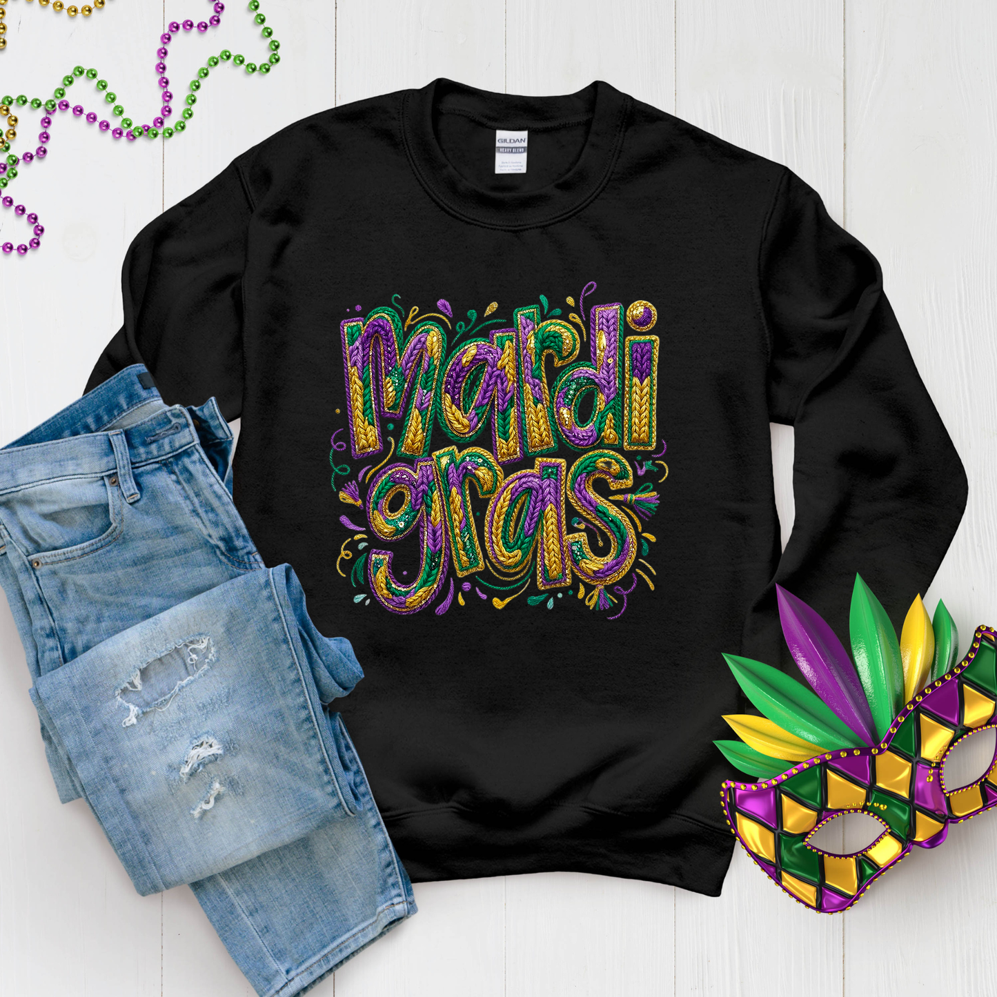 Black sweatshirt with 'Mardi Gras' text, denim shorts, and a Mardi Gras mask on a white background