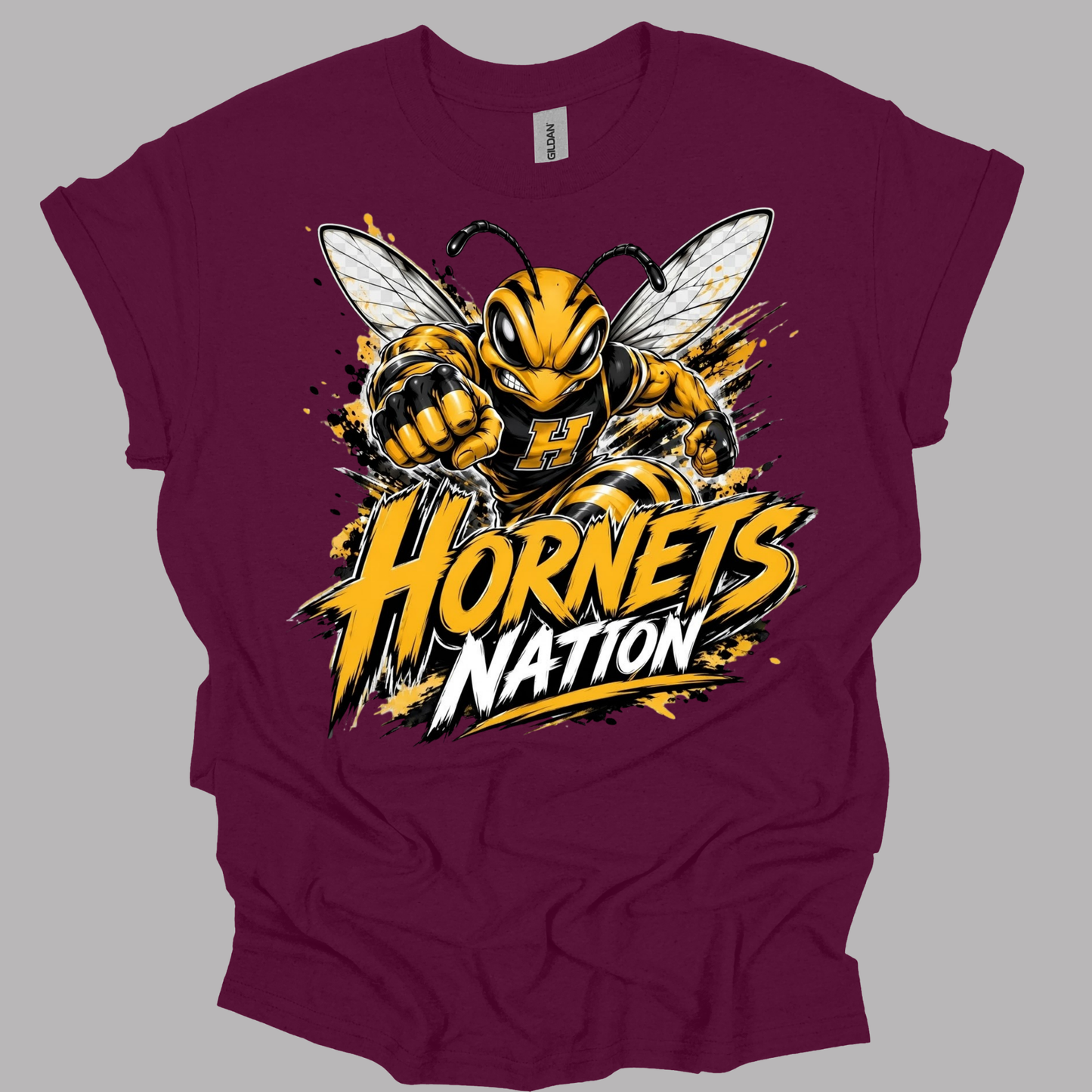 A maroon short-sleeve t-shirt with a large graphic of a yellow and black hornet and the text 'Hornets Nation' in yellow, white, and black, displayed on a solid gray background.
