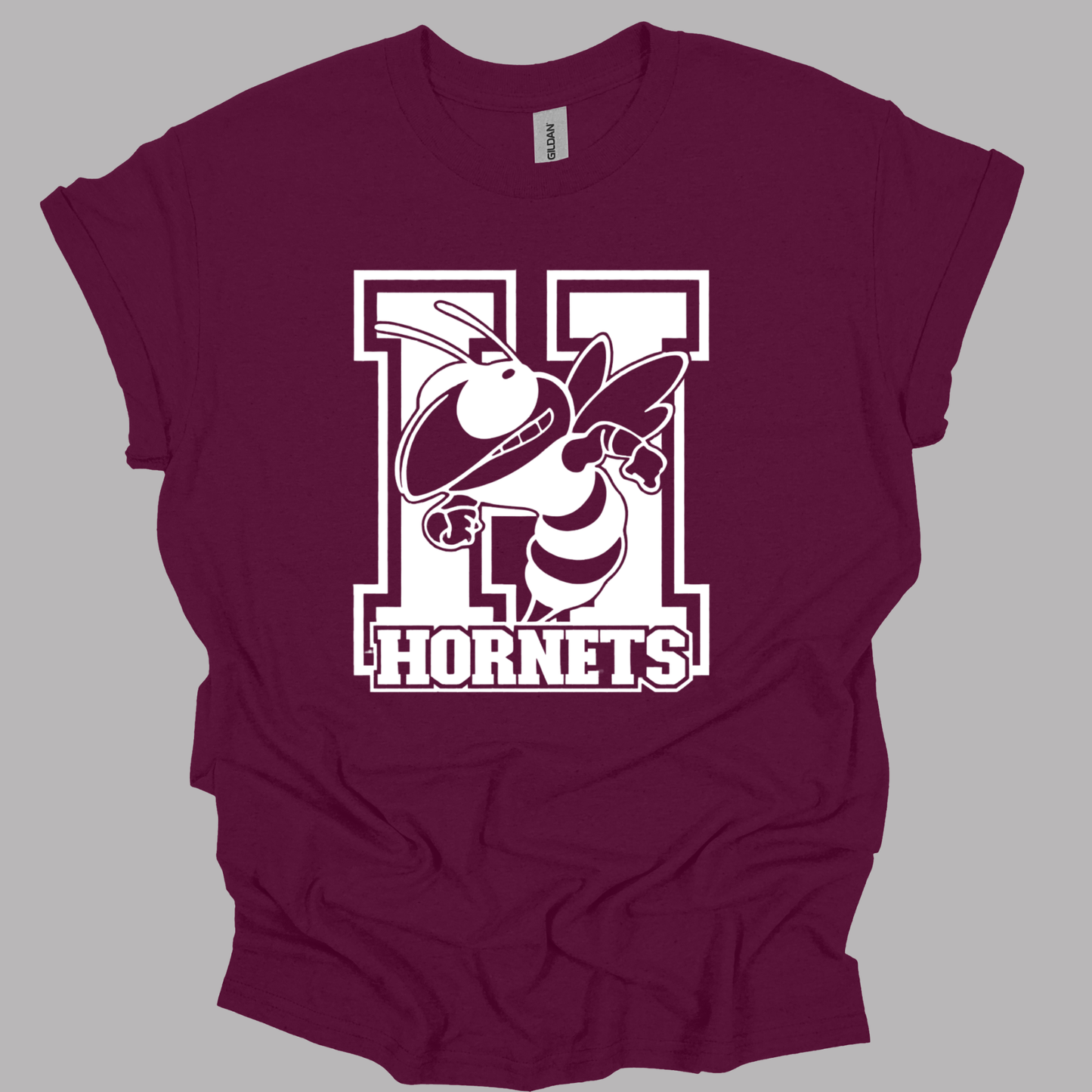 A maroon short-sleeve t-shirt with a white graphic of a hornet mascot inside a large letter 'H' and the word 'HORNETS' printed on the front, displayed on a solid gray background.