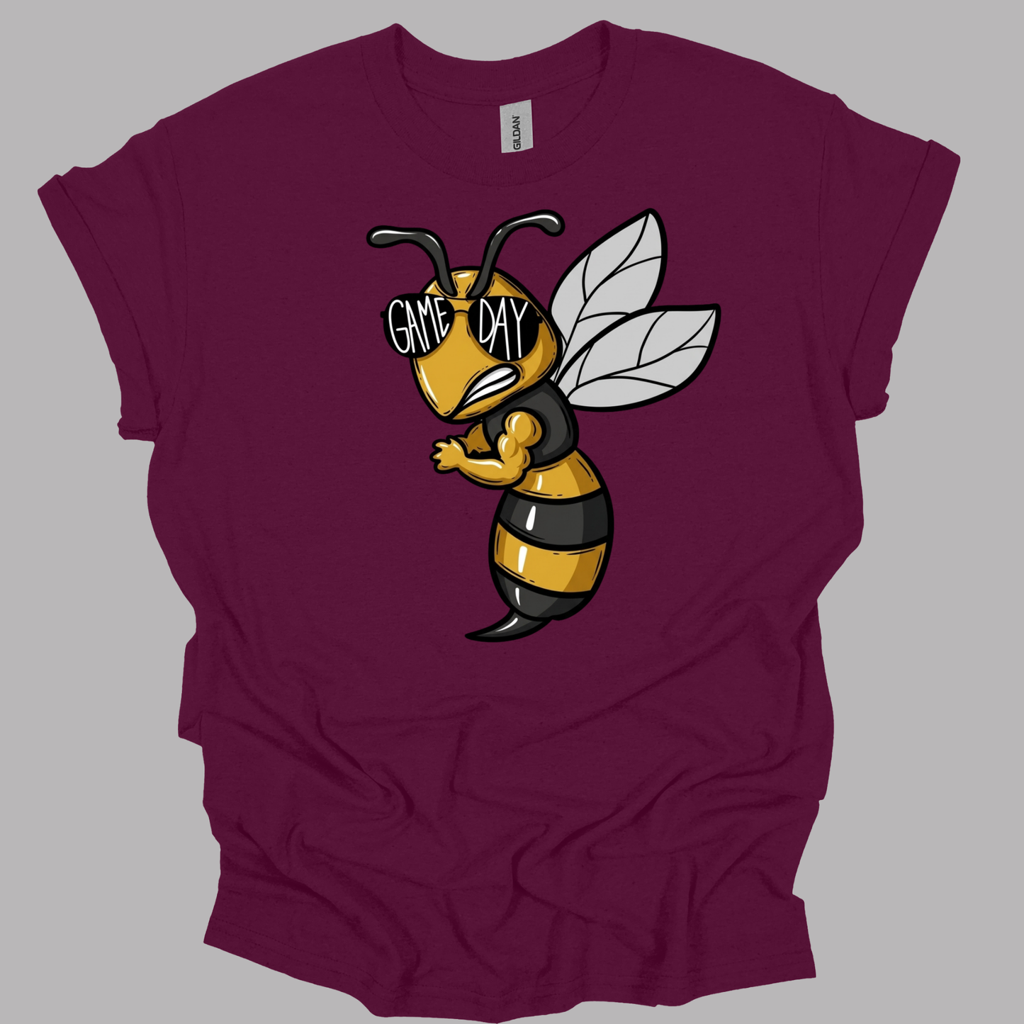 A maroon short-sleeve t-shirt with a cartoon graphic of a bee wearing black and yellow stripes and sunglasses that read 'GAME DAY'.