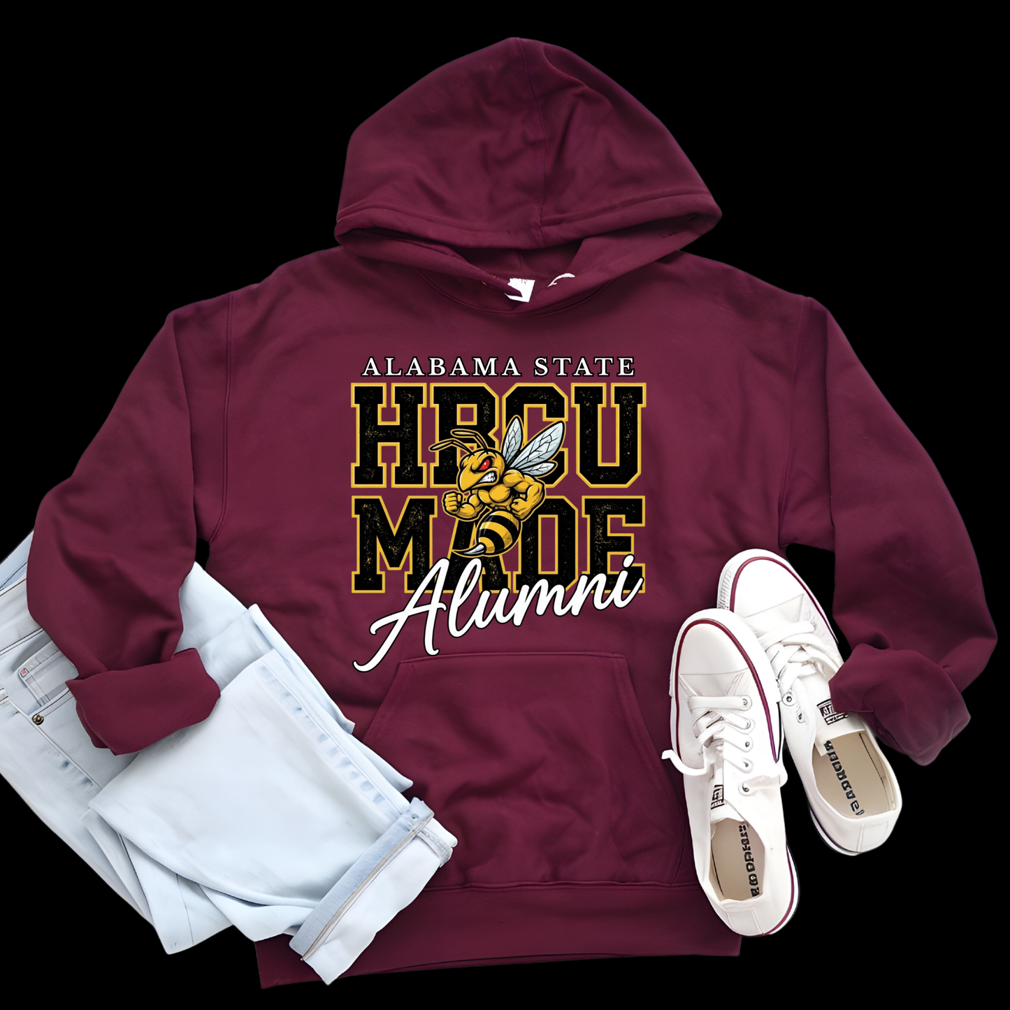 A maroon pullover hoodie with a large yellow and black hornet graphic and the words 'Hornets Nation' on the front, styled in a flat lay with light blue jeans and white sneakers on a black background.