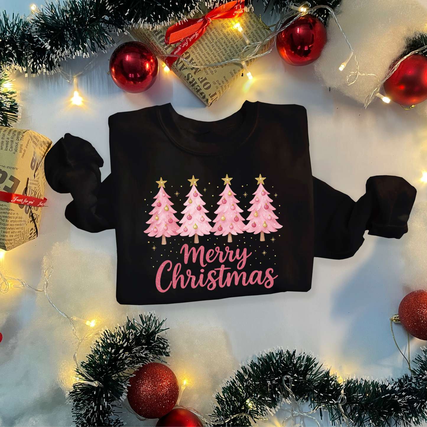 Black sweatshirt with Christmas tree design and 'Merry Christmas' text, surrounded by festive decorations.