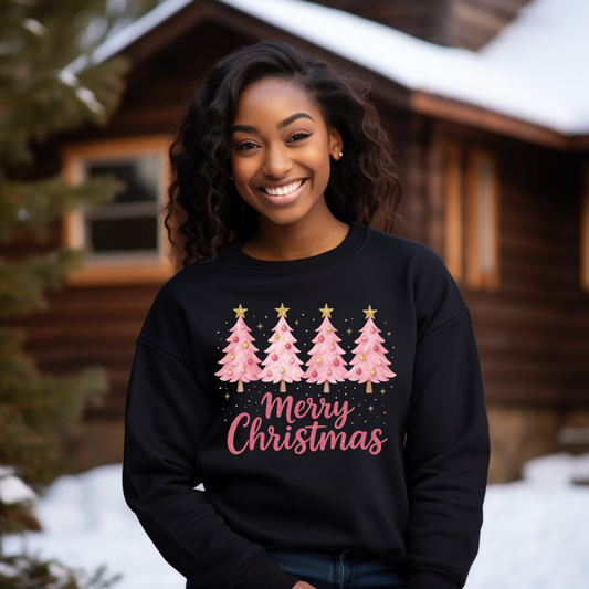 Woman wearing a black sweatshirt with Christmas tree design and 'Merry Christmas' text, standing in front of a wooden cabin.
