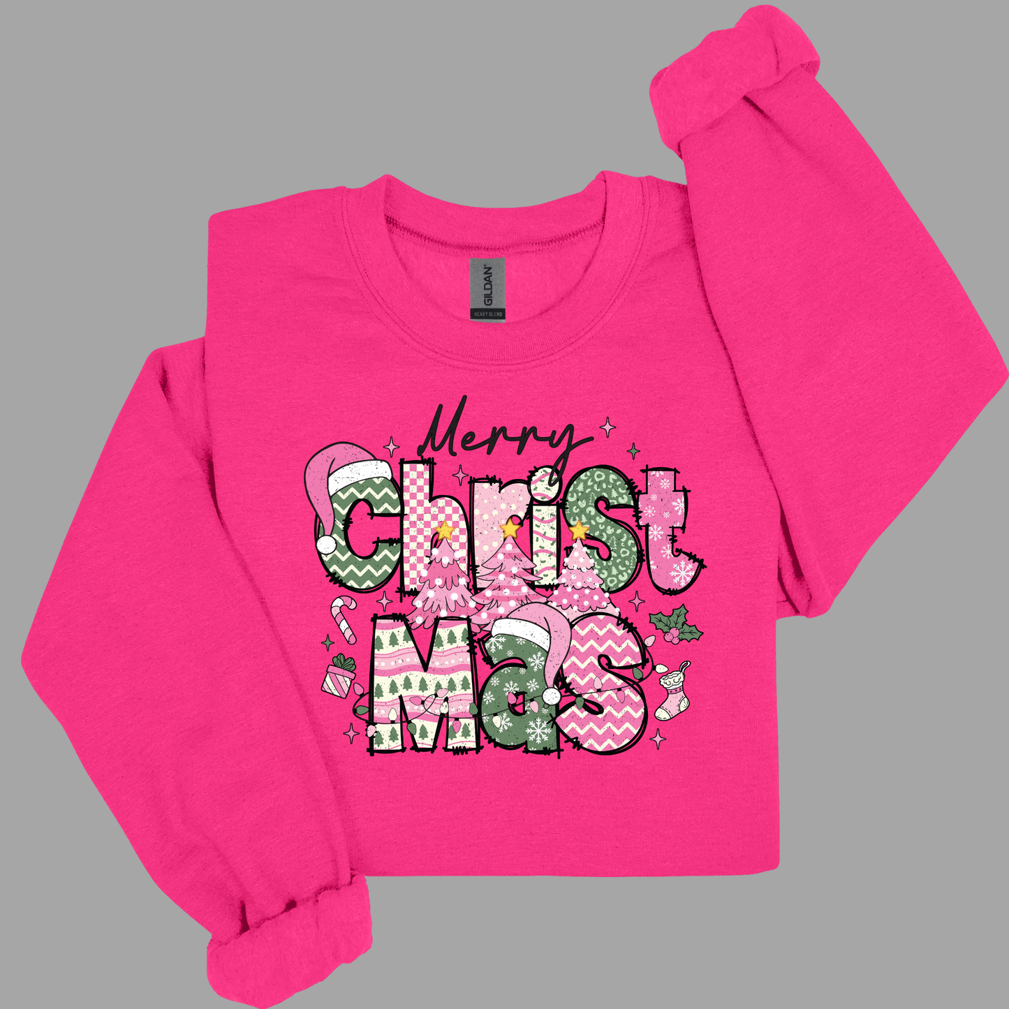 Pink long-sleeve shirt with 'Merry Christ M's' text and Christmas-themed graphics on a gray background