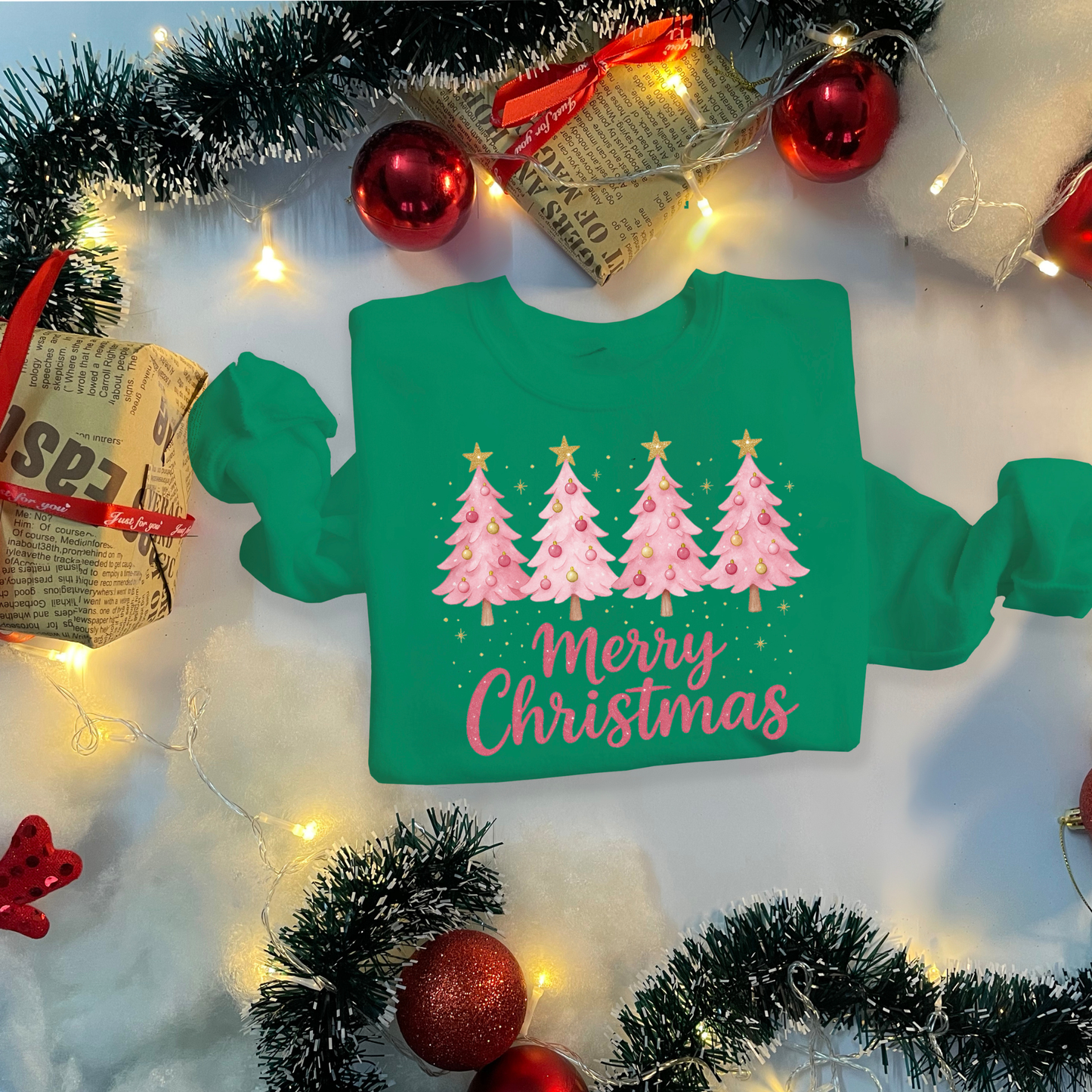 Green sweatshirt with Christmas tree design and 'Merry Christmas' text, surrounded by festive decorations.