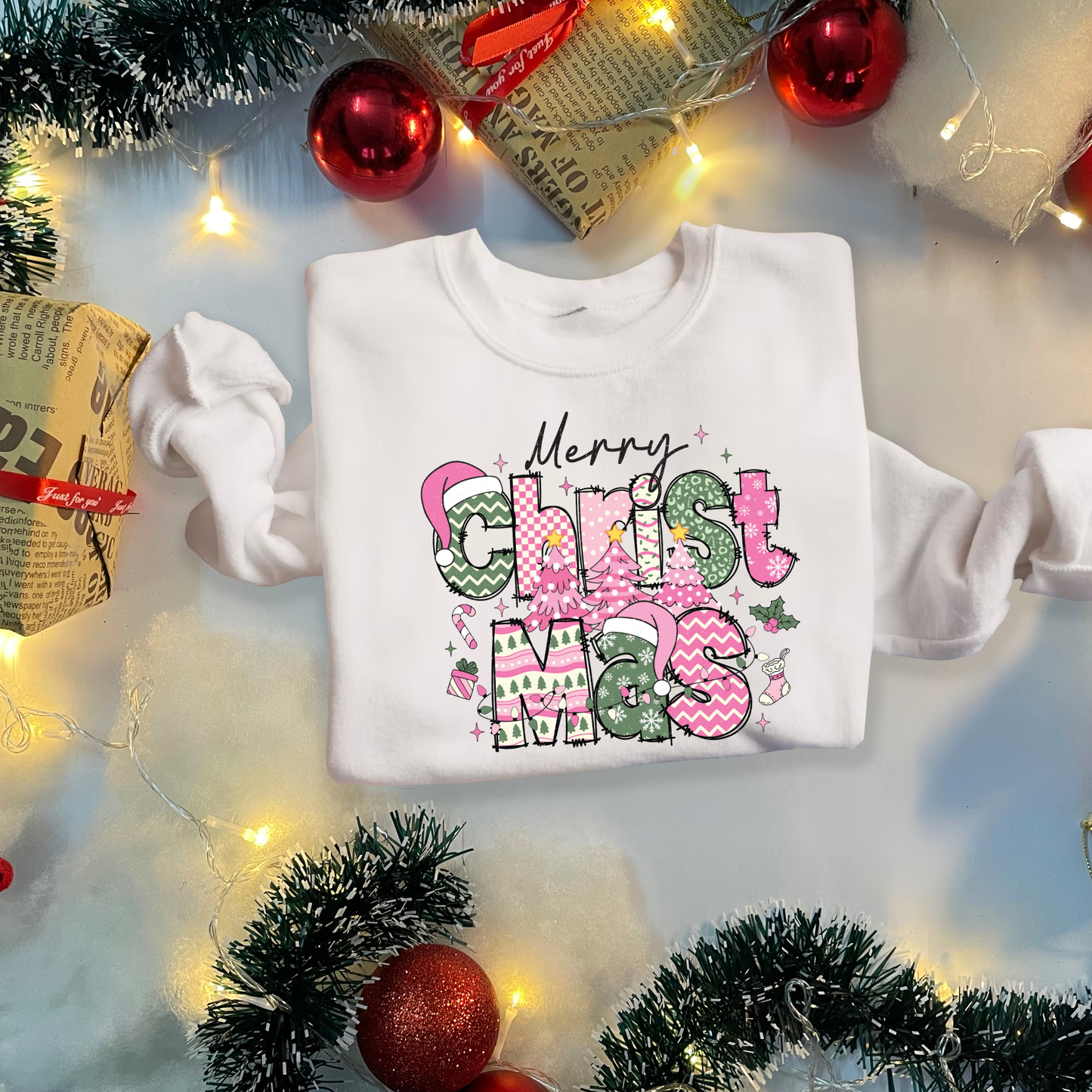 White sweatshirt with 'Merry Christmas' text surrounded by holiday decorations on a light background