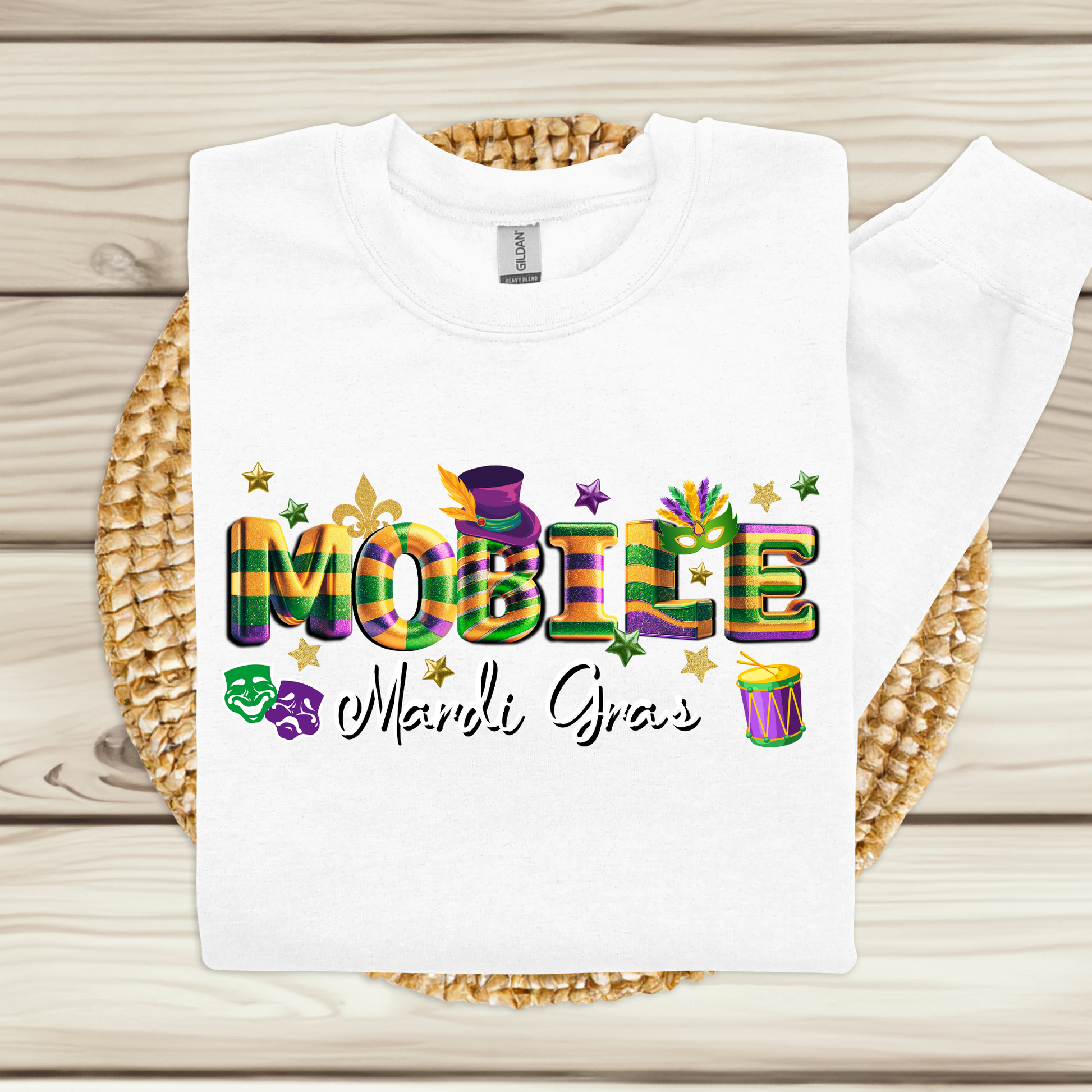 White t-shirt with colorful 'MOBILE Mardi Gras' text on a woven mat.