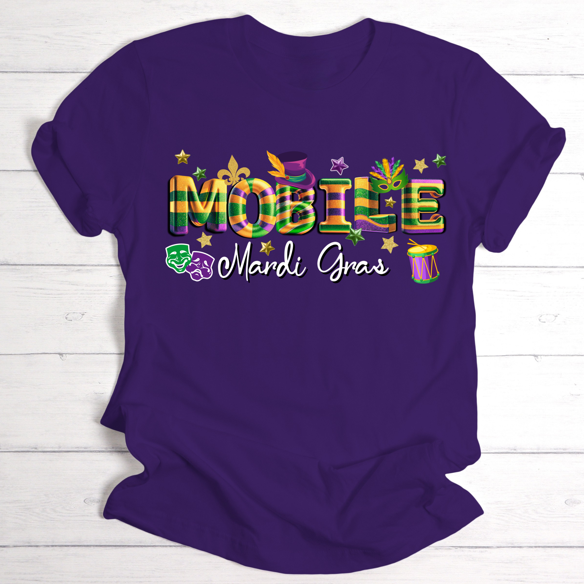 Purple t-shirt with colorful 'Mobile Mardi Gras' text on a white wooden background