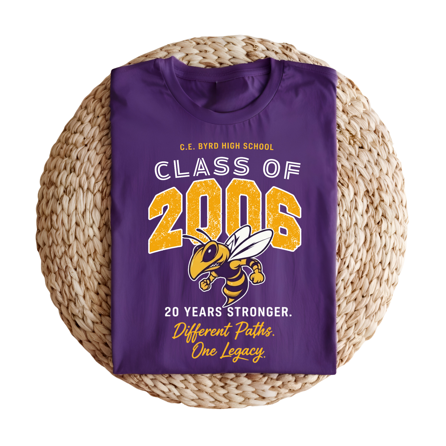 A folded purple t-shirt with a 'Class of 2006' graduation graphic, displayed on a round woven straw mat against a white background.