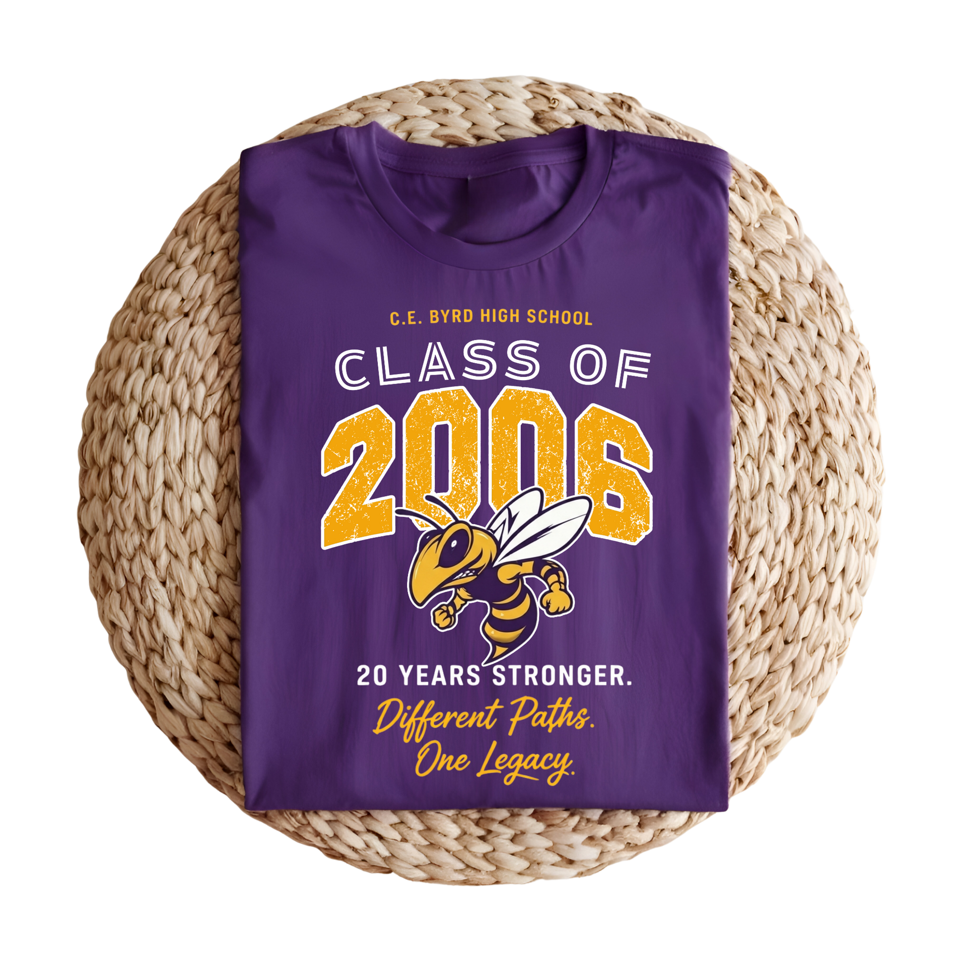 A folded purple t-shirt with a 'Class of 2006' graduation graphic, displayed on a round woven straw mat against a white background.