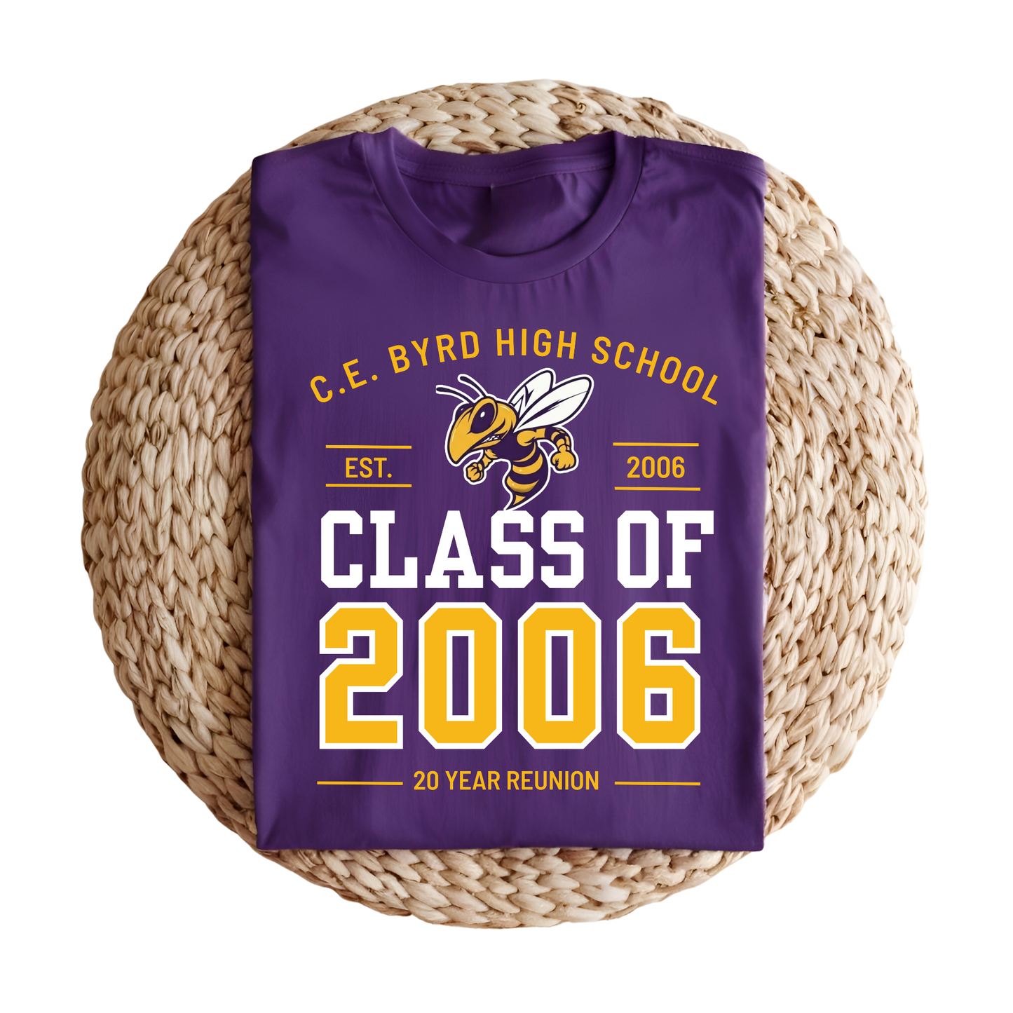 A folded purple t-shirt with a 'Class of 2006' 20-year reunion graphic, displayed on a round woven straw mat against a white background.