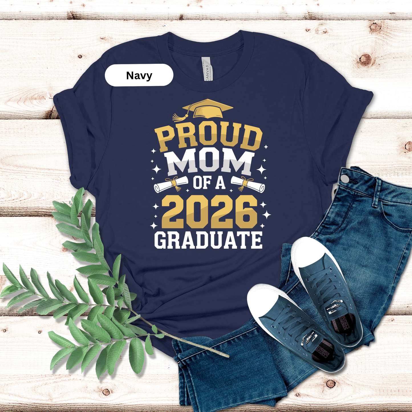 Navy t-shirt with 'Proud Mom of a 2026 Graduate' text on a wooden surface with jeans and shoes.