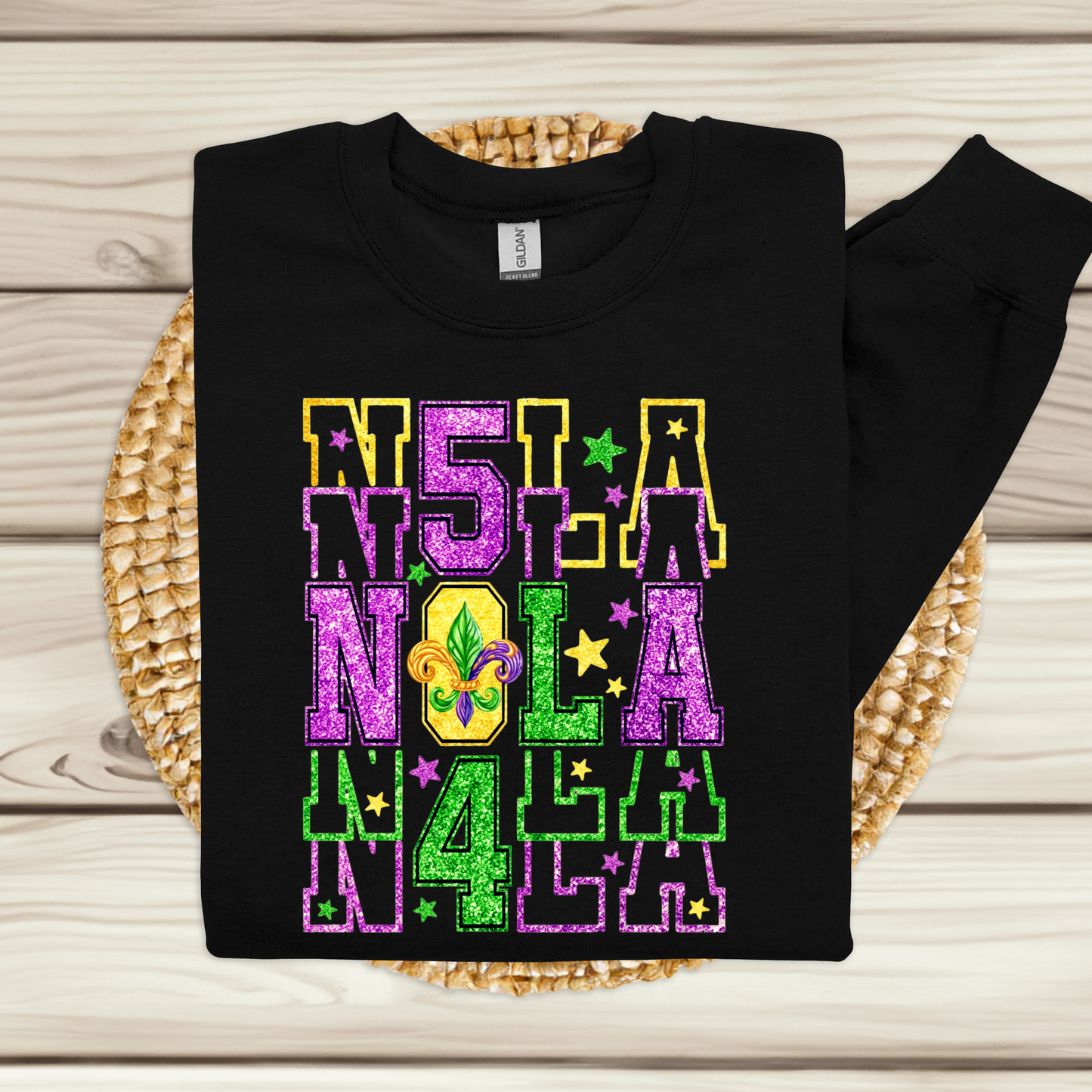 Black sweatshirt with colorful 'NOLA' text design on a wooden surface